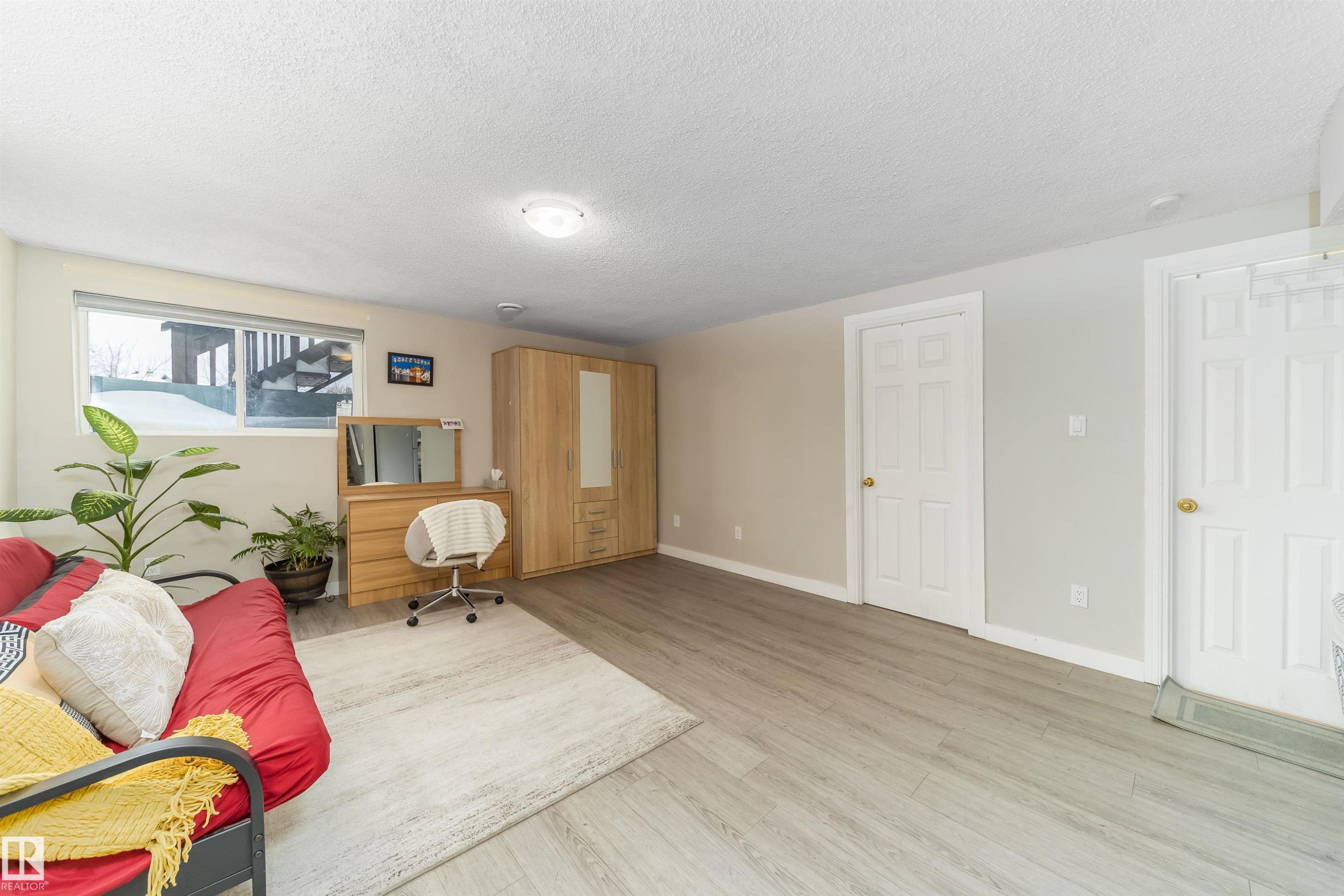 Sitting room featuring a textured ceiling and light wood-style floors - 8518 6 Av, Edmonton, AB - Indoor