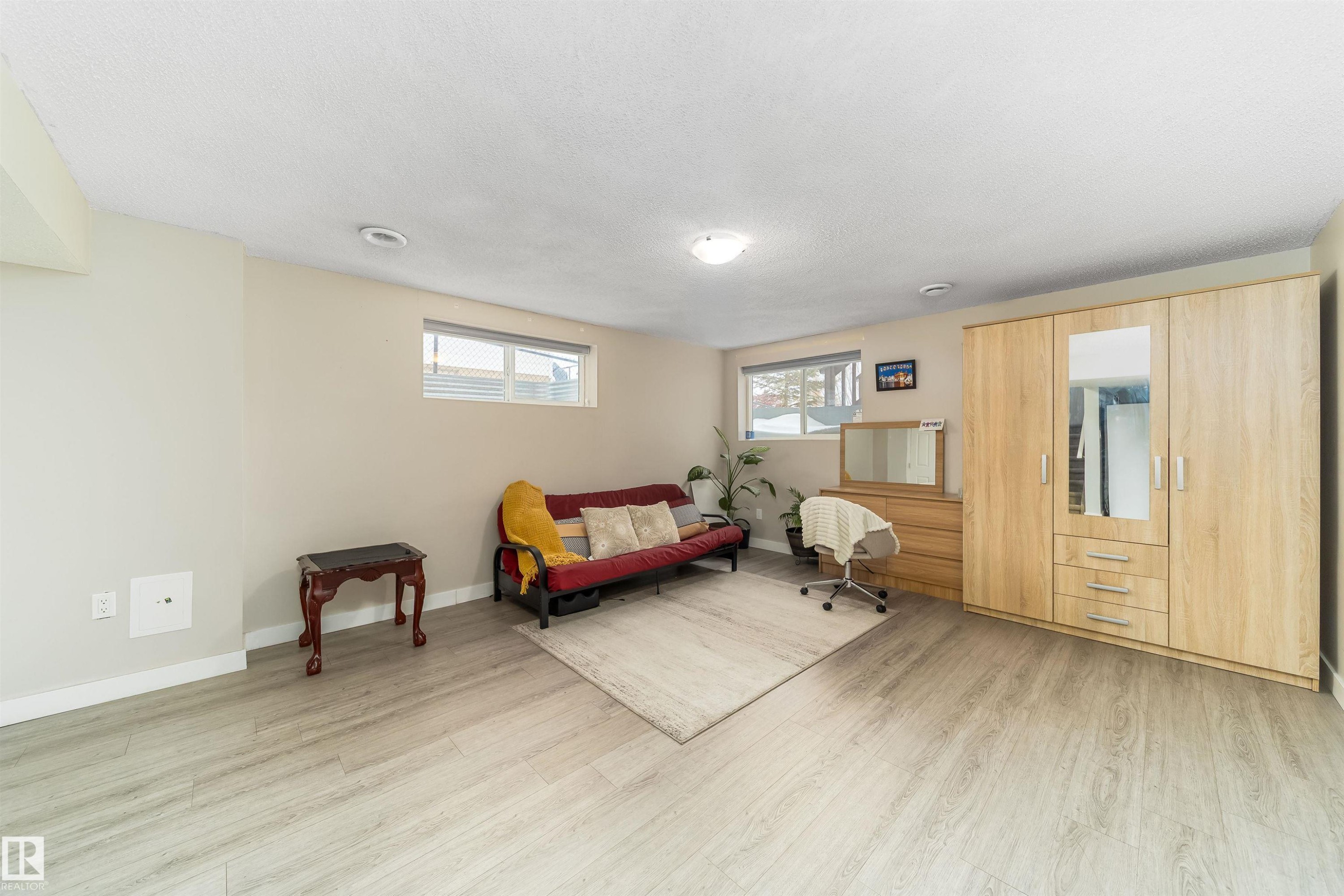 Living area with light wood-type flooring and a textured ceiling - 8518 6 Av, Edmonton, AB - Indoor