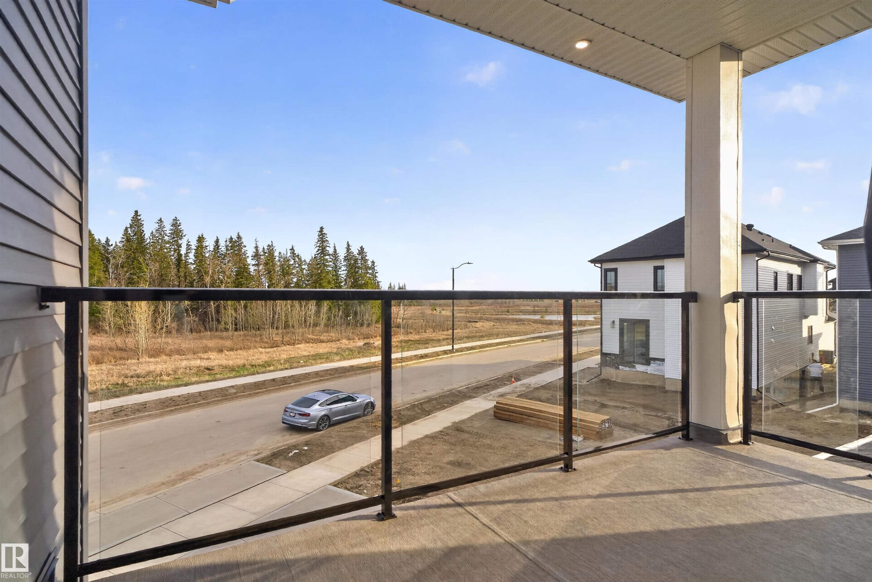 Exterior balcony featuring concrete flooring, black metal railings with glass inserts, and a white soffit with recessed lighting - 27 Redpoll Wynd, St. Albert, AB - Outdoor With Balcony With Exterior
