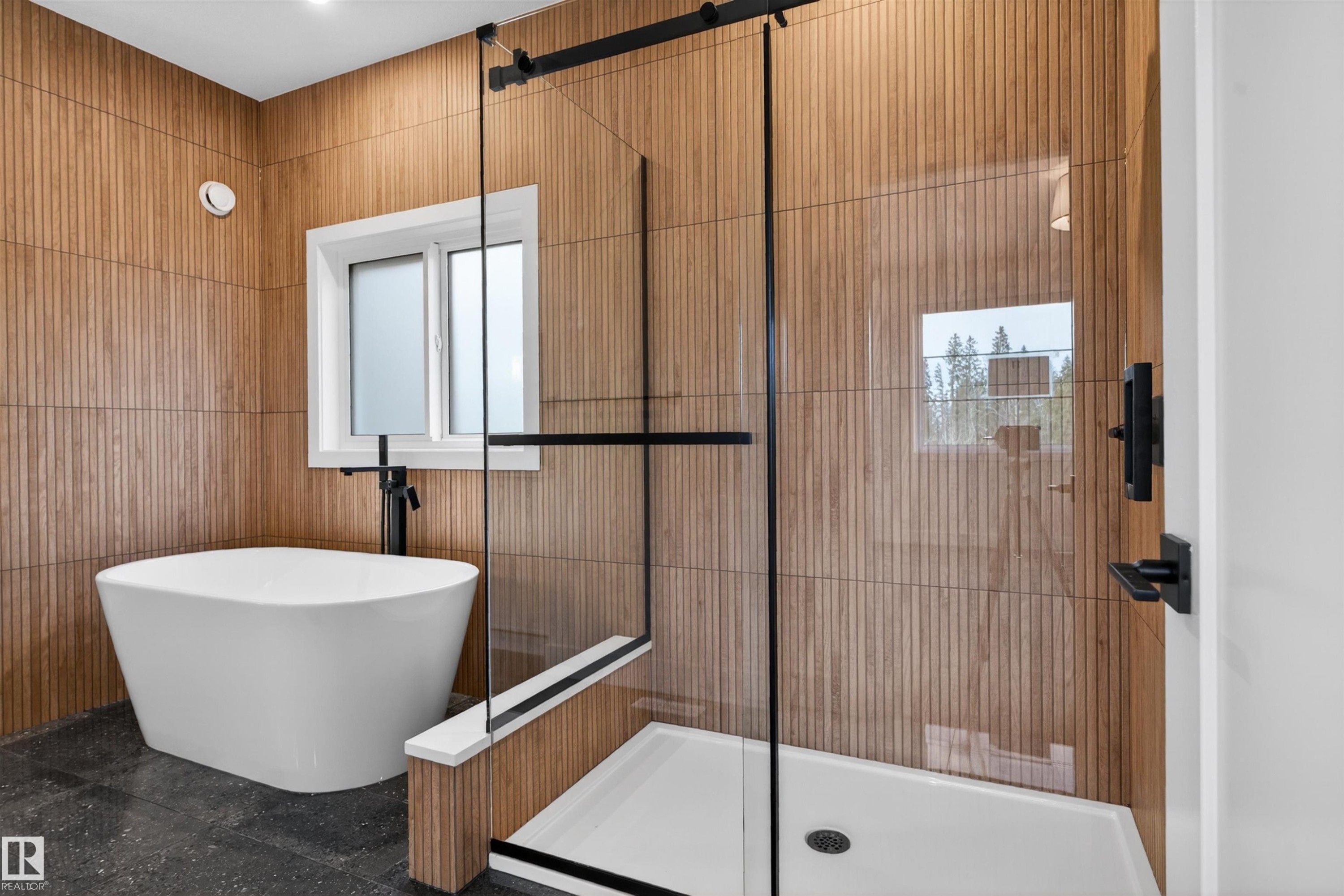 Freestanding soaking tub with black hardware, complementing a glass-enclosed shower featuring a white shower pan and black framing - 27 Redpoll Wynd, St. Albert, AB - Indoor Photo Showing Bathroom