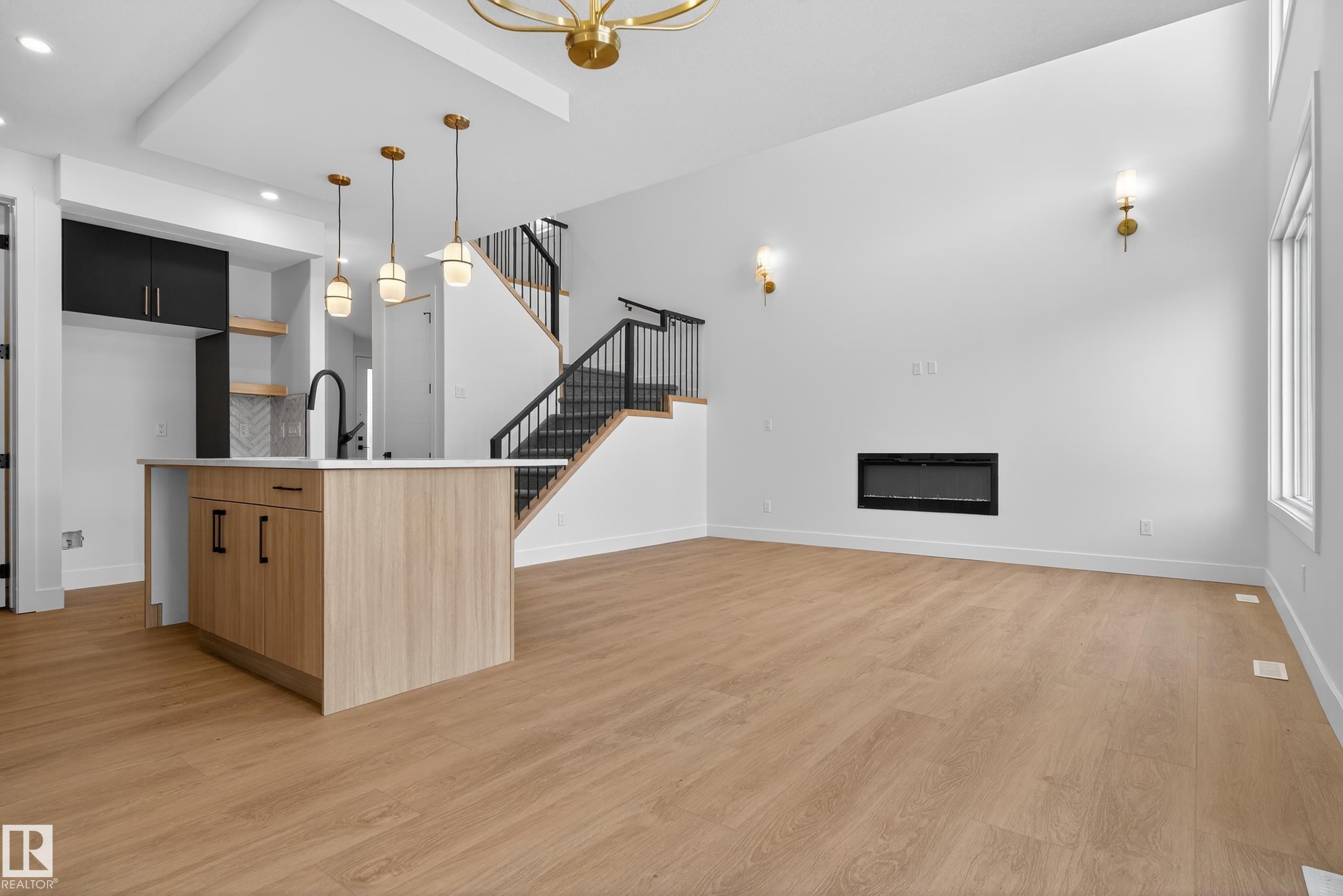 Kitchen with modern cabinets, light wood finished floors, open shelves, a glass covered fireplace, and a high ceiling - 19 Rosa Crescent, St. Albert, AB - Indoor With Fireplace