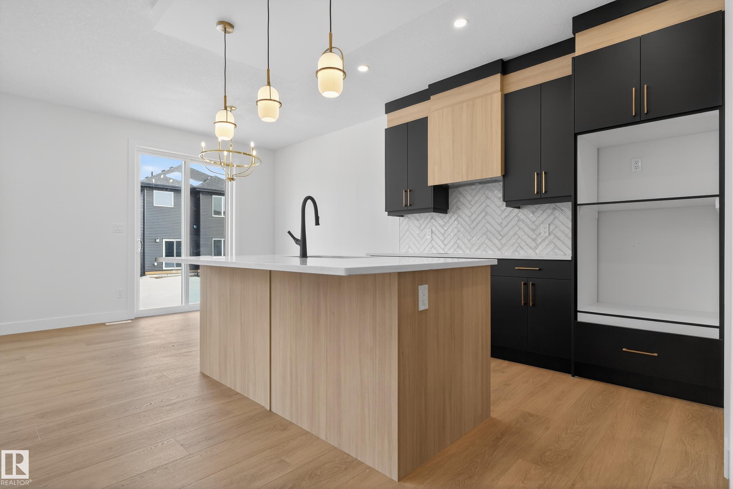 Kitchen with two tone color scheme, tasteful backsplash, light wood finished floors, a center island with sink, and a chandelier - 19 Rosa Crescent, St. Albert, AB - Indoor Photo Showing Kitchen