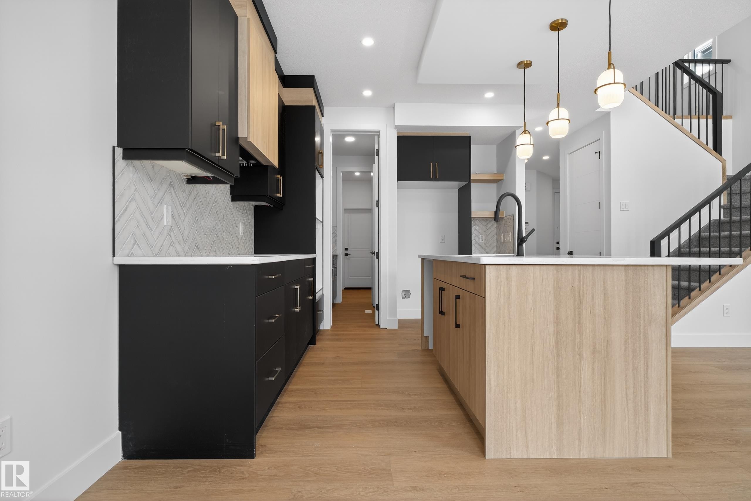 Kitchen featuring dual tone cabinetry, a kitchen island with sink, modern cabinets, light wood-style flooring, and decorative backsplash - 19 Rosa Crescent, St. Albert, AB - Indoor Photo Showing Other Room