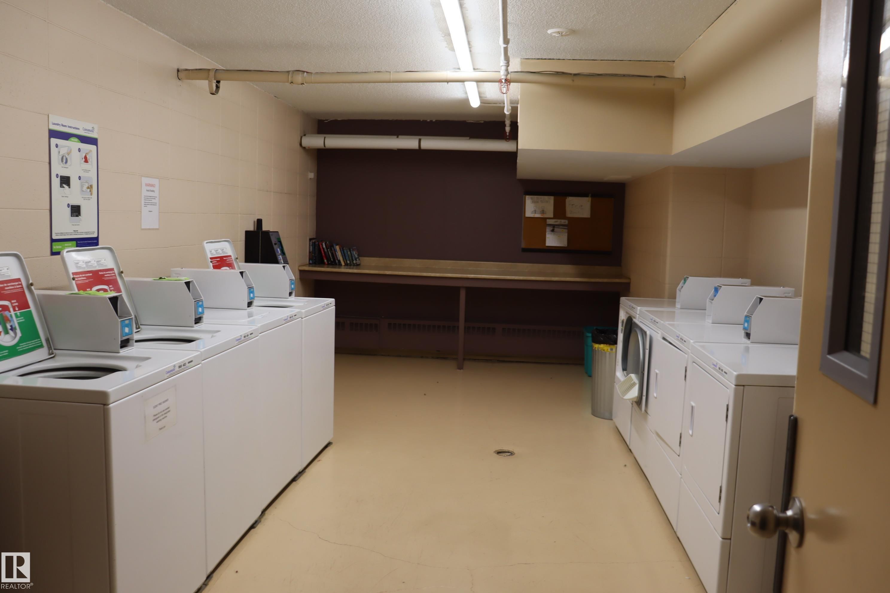 Coin operated laundry with folding table and scrub sink. - #203 9028 Jasper Ave Nw, Edmonton, AB - Indoor Photo Showing Laundry Room