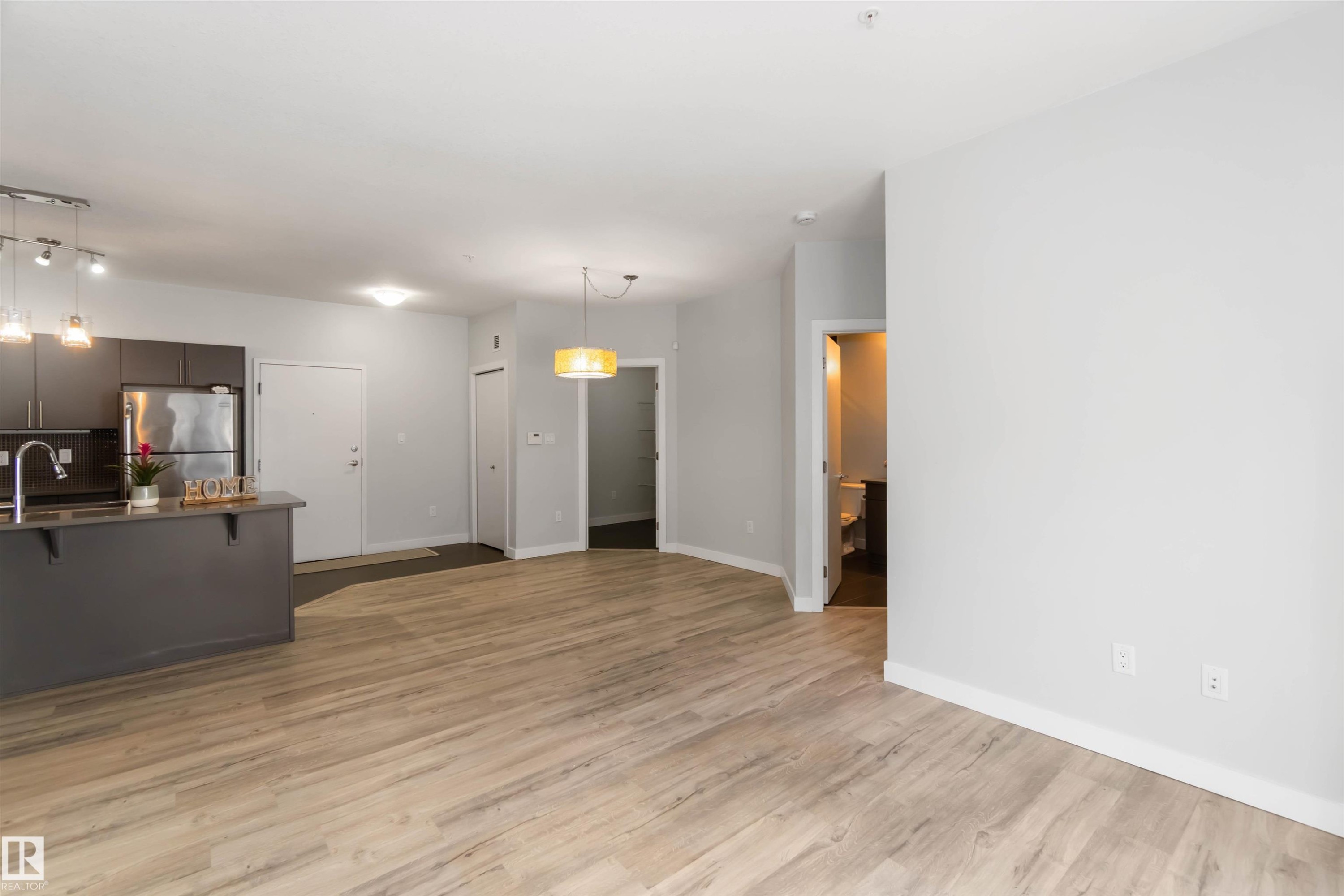 Unfurnished living room featuring light wood-type flooring and baseboards - 107 10611 117 Street, Edmonton, AB - Indoor Photo Showing Other Room