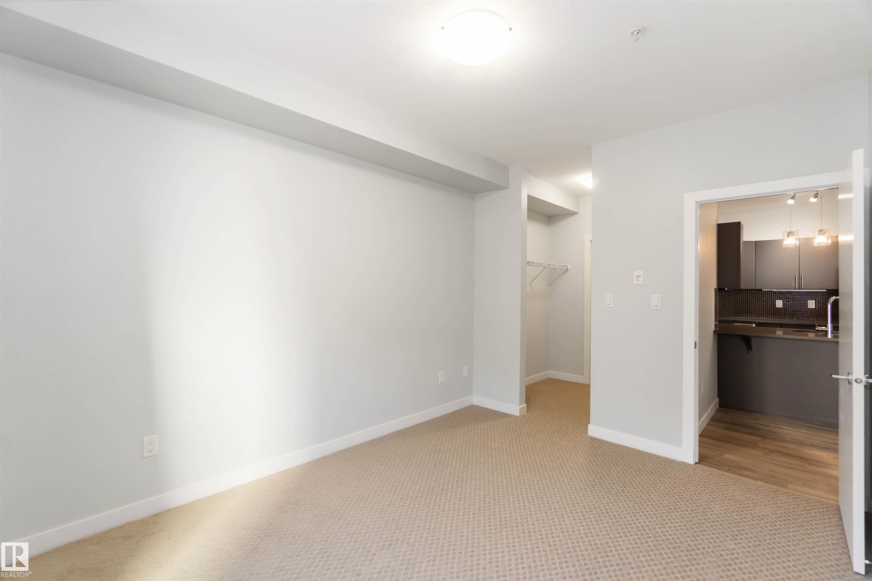 Unfurnished bedroom with light colored carpet, a spacious closet, and ensuite bathroom - 107 10611 117 Street, Edmonton, AB - Indoor Photo Showing Other Room