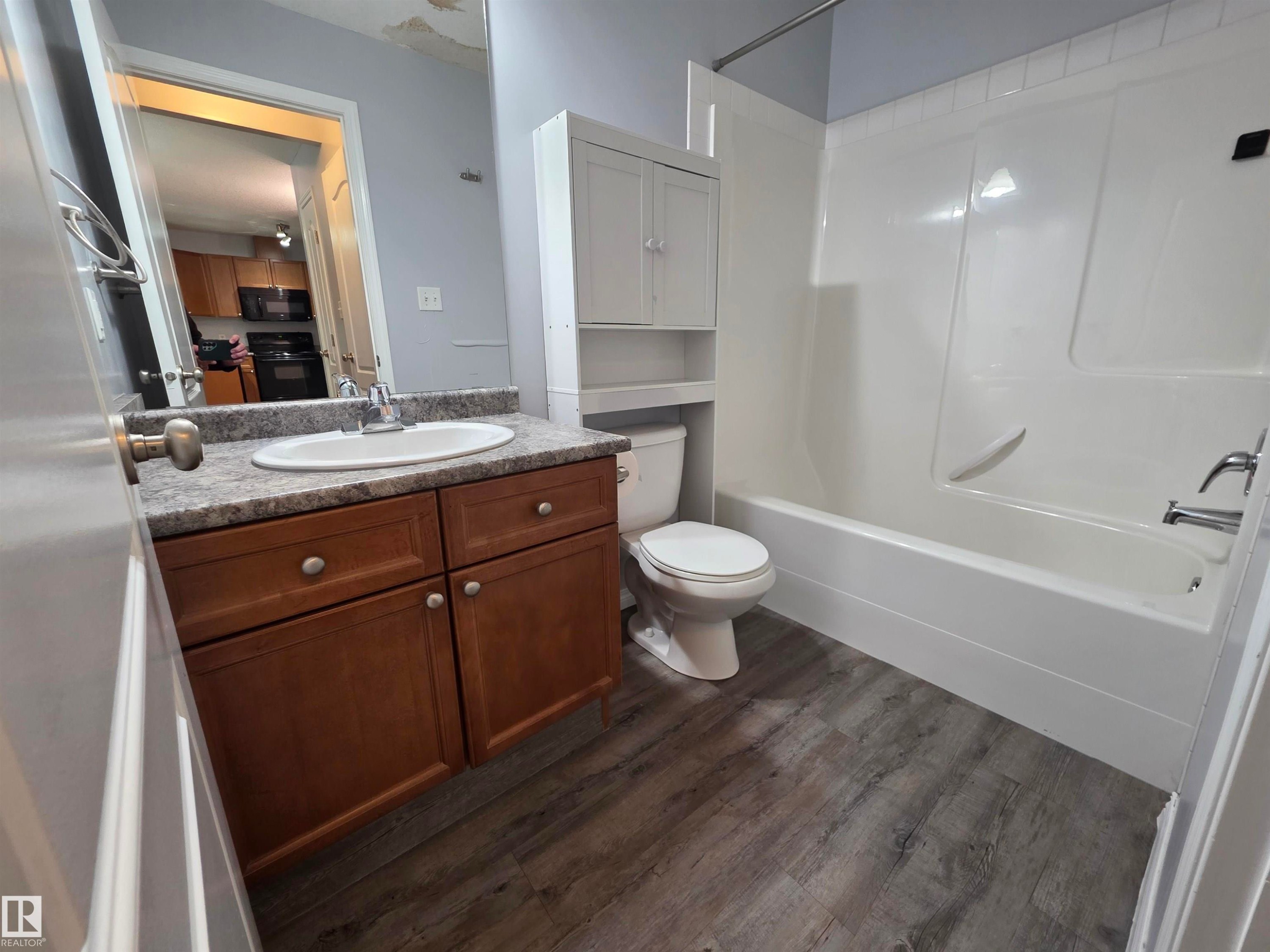 Bathroom featuring vanity, bathtub / shower combination, and dark wood-style flooring - 106 4903 47 Avenue, Stony Plain, AB - Indoor Photo Showing Bathroom