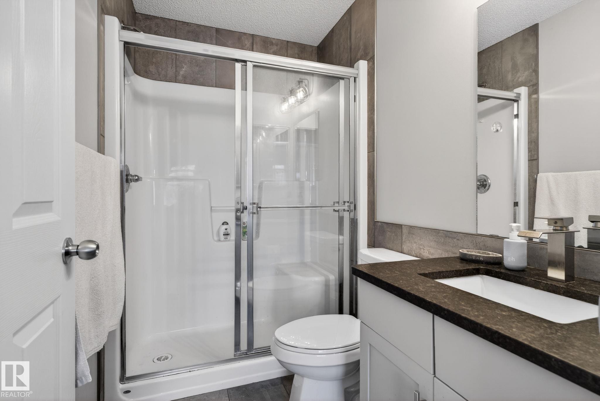 Bathroom with vanity, a stall shower, a textured ceiling, and dark wood-style flooring - 60 1804 70 Street, Edmonton, AB - Indoor Photo Showing Bathroom