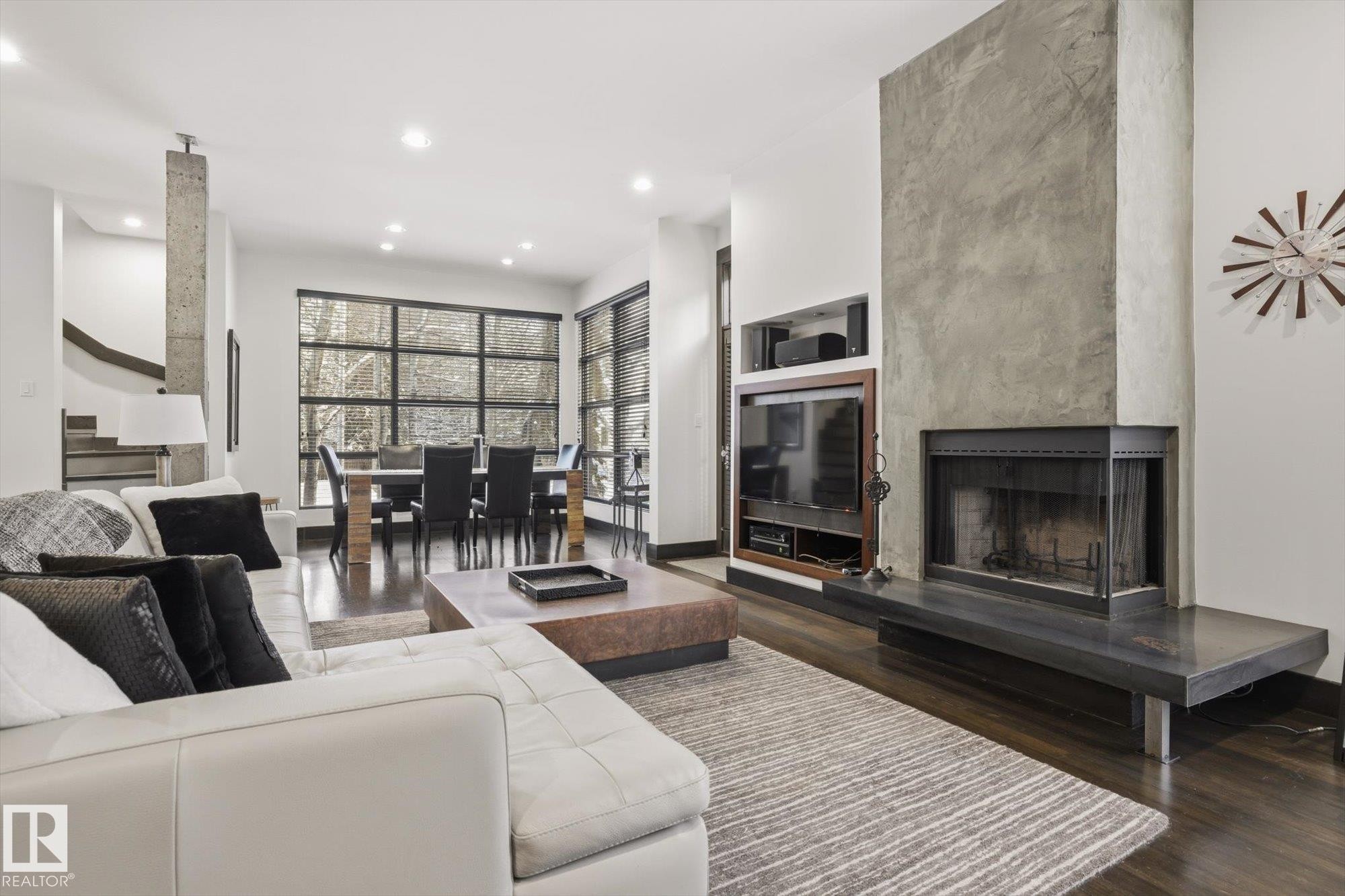 Living room with a large fireplace, wood finished floors, recessed lighting, built in shelves, and stairs - 9012 98 Street, Edmonton, AB - Indoor Photo Showing Living Room With Fireplace