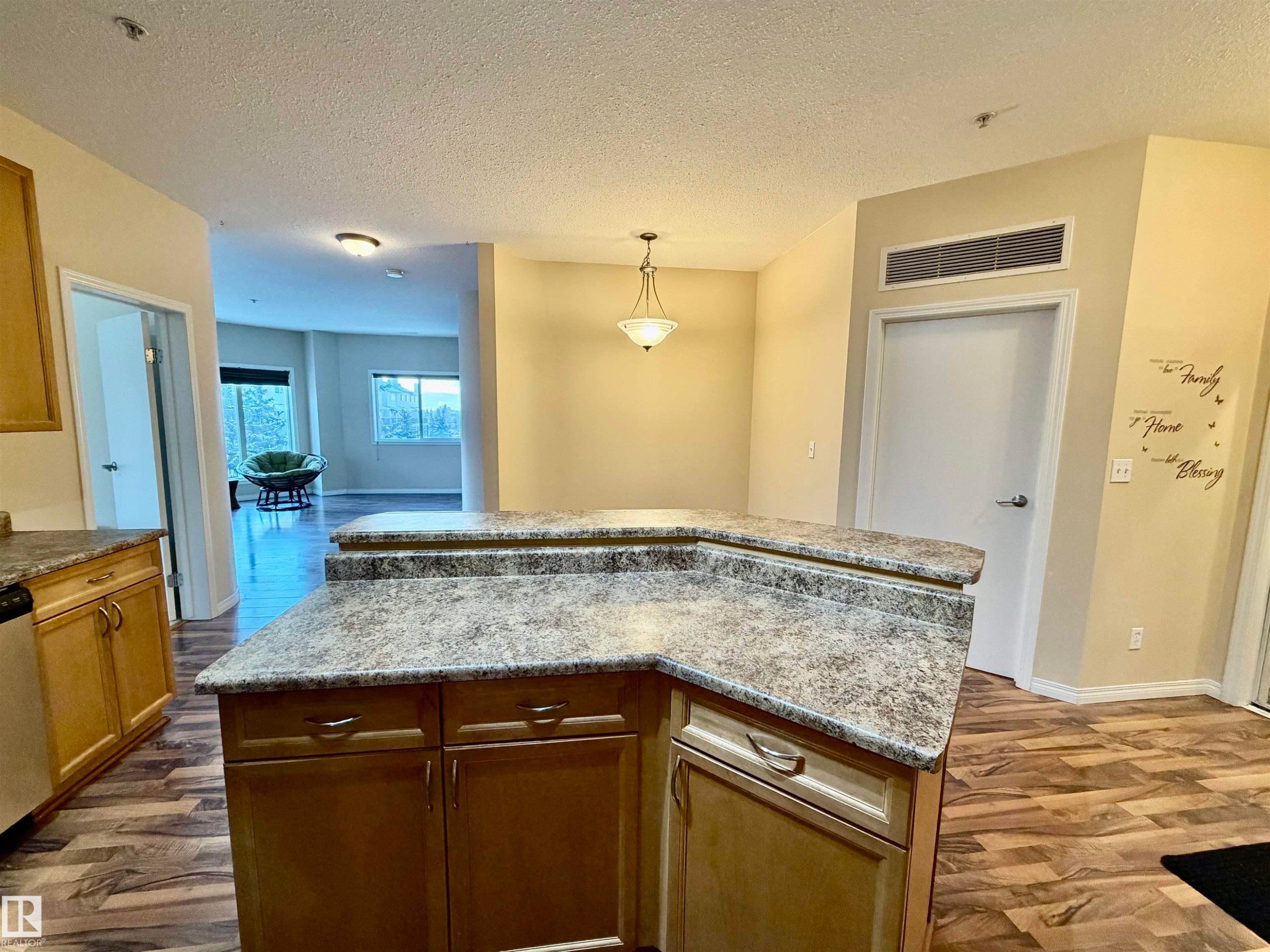 Kitchen with decorative light fixtures, a textured ceiling, dark wood finished floors, a kitchen island, and dishwasher - 321 4304 139 Avenue, Edmonton, AB - Indoor Photo Showing Kitchen