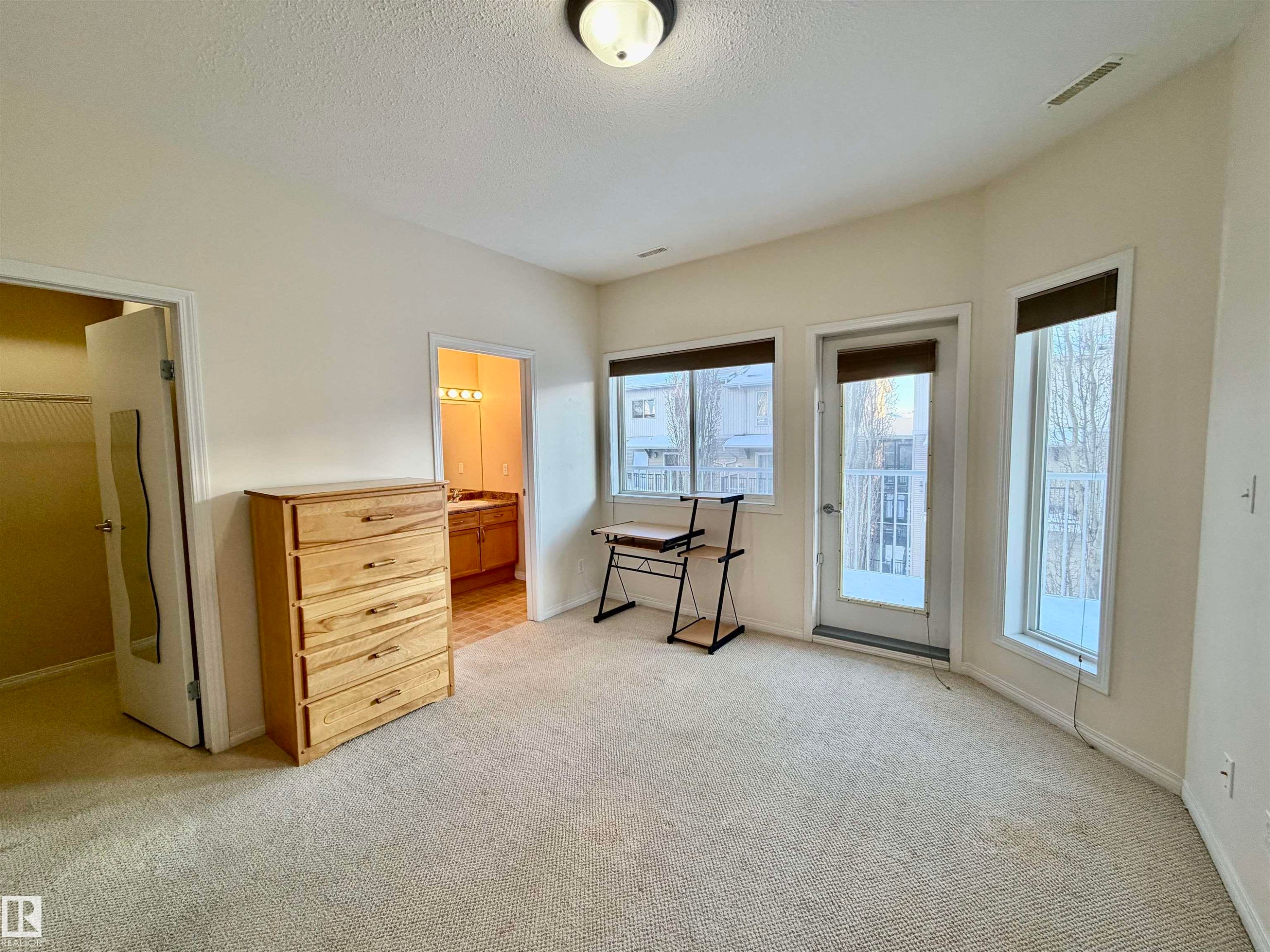 Bedroom featuring light carpet, access to outside, and a textured ceiling - 321 4304 139 Avenue, Edmonton, AB - Indoor