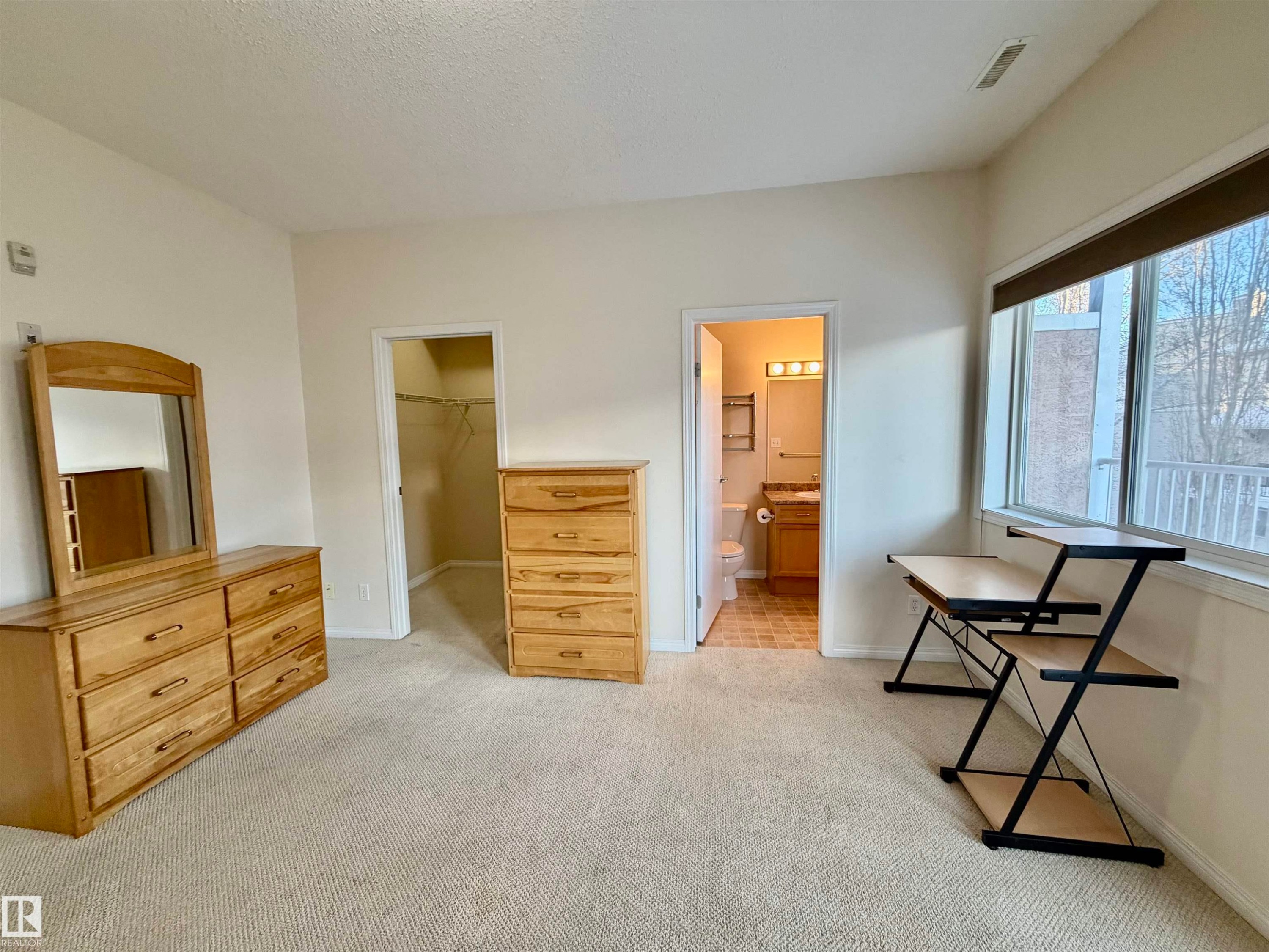 Bedroom with a spacious closet, light carpet, ensuite bath, and a textured ceiling - 321 4304 139 Avenue, Edmonton, AB - Indoor