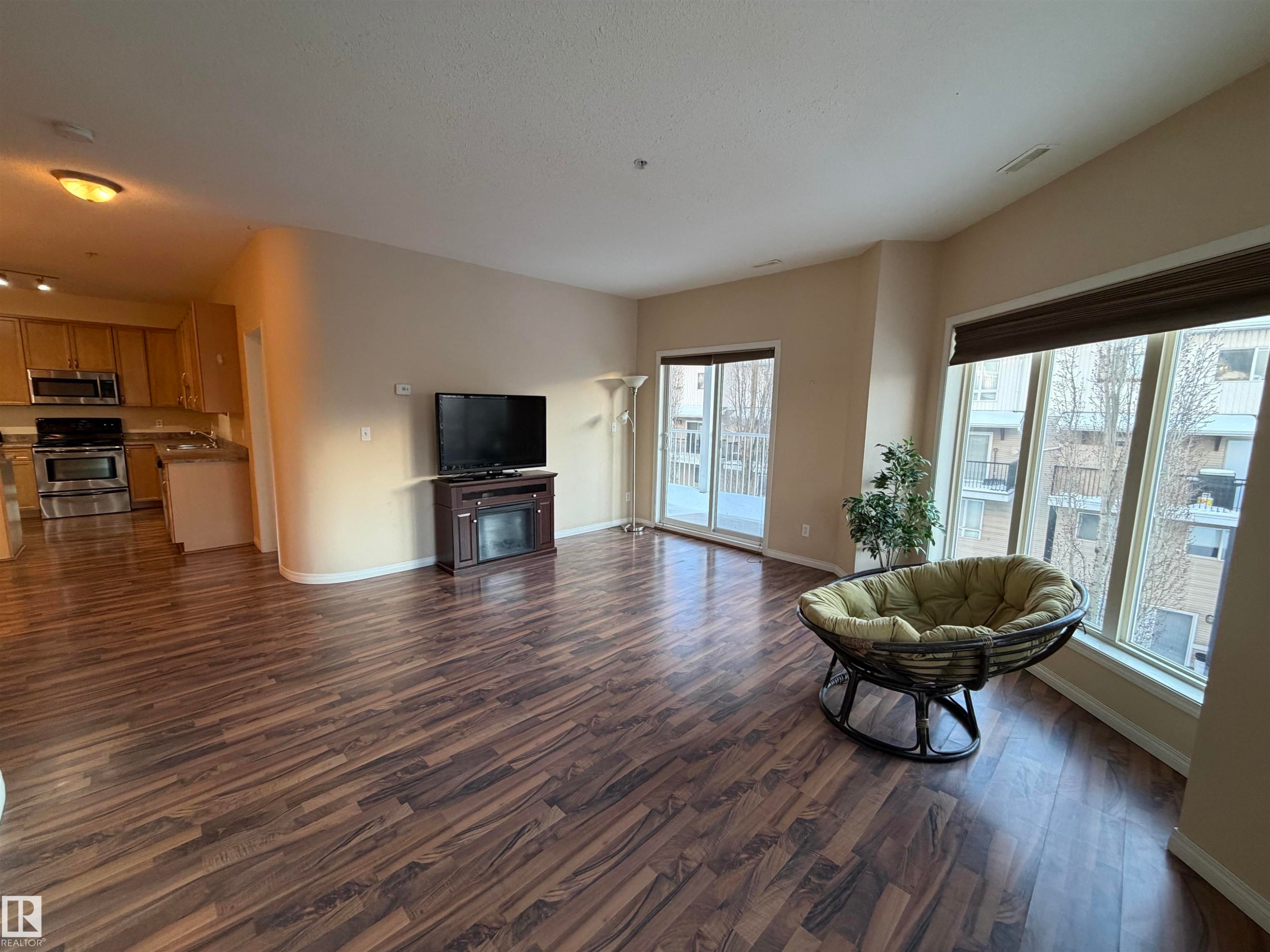 Living area with dark wood-type flooring and a fireplace - 321 4304 139 Avenue, Edmonton, AB - Indoor Photo Showing Living Room