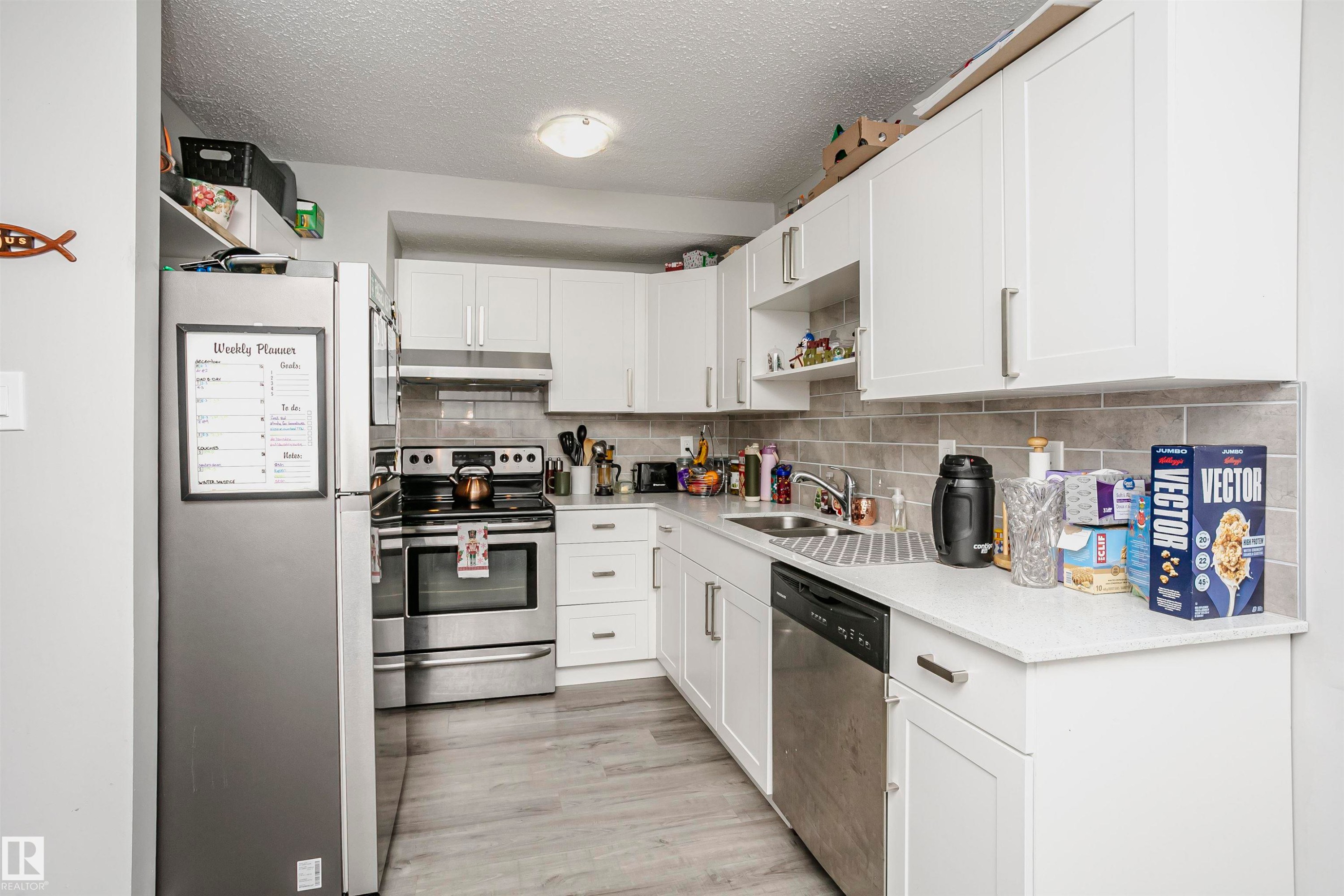 Kitchen with appliances with stainless steel finishes, open shelves, a textured ceiling, white cabinets, and under cabinet range hood - 3103 109 Street, Edmonton, AB - Indoor Photo Showing Kitchen With Double Sink
