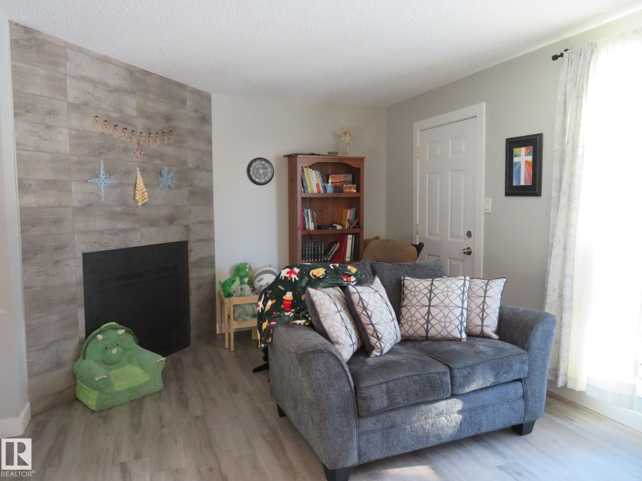 Living room featuring wood finished floors, a tile fireplace, and a textured ceiling - 3103 109 Street, Edmonton, AB - Indoor Photo Showing Living Room With Fireplace