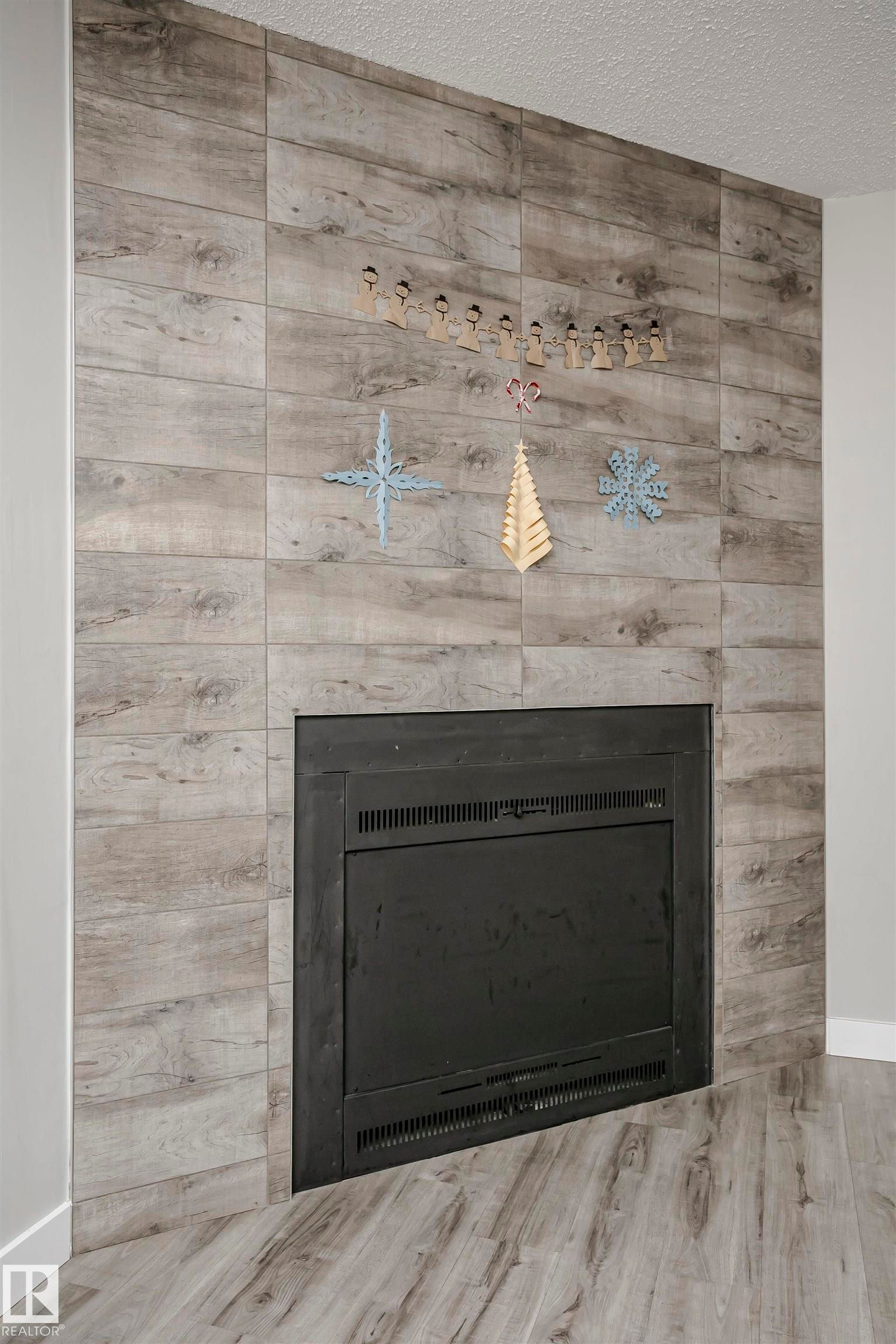 Detailed view of a fireplace, a textured ceiling, and wood finished floors - 3103 109 Street, Edmonton, AB - Indoor Photo Showing Other Room With Fireplace