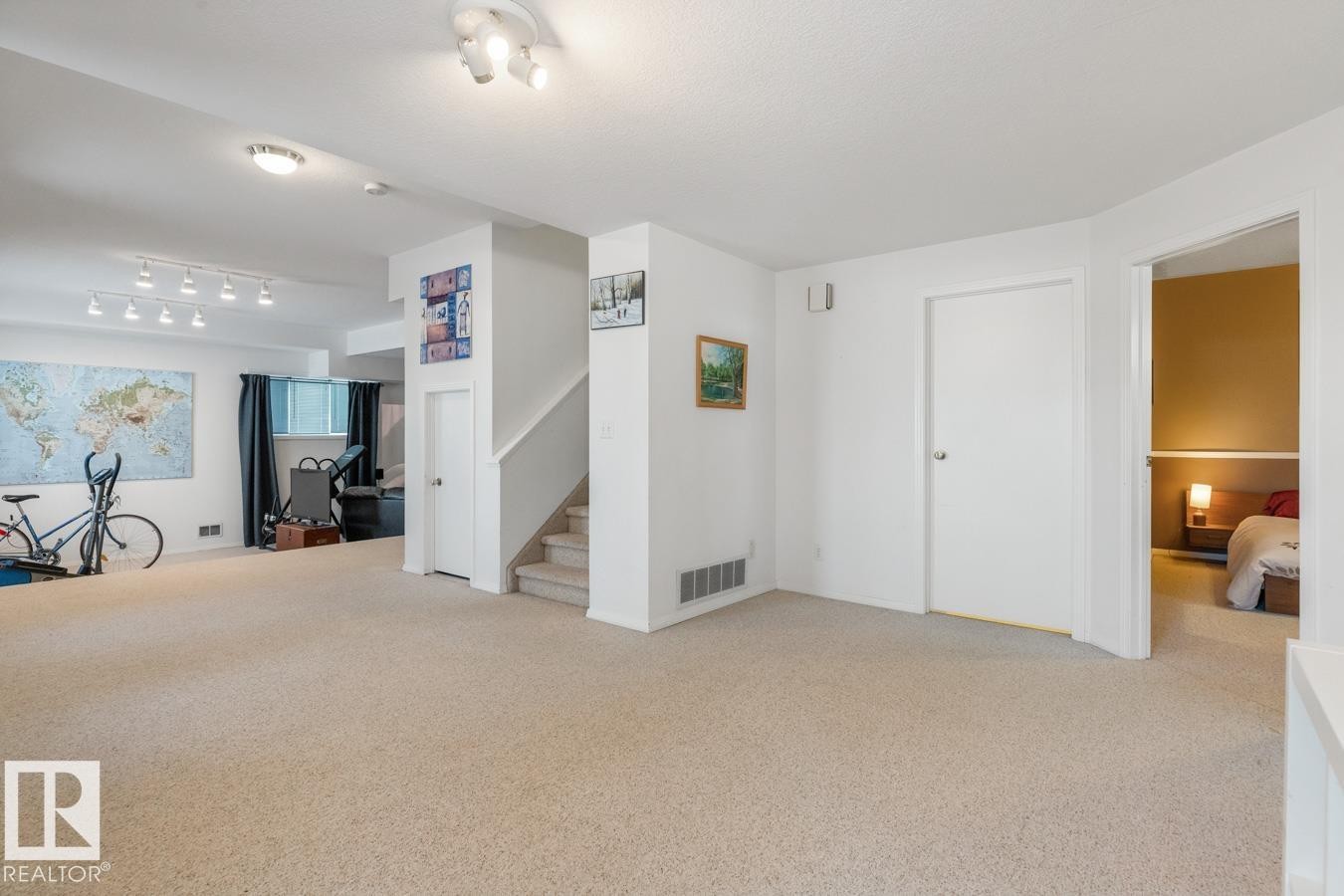 Unfurnished living room with light colored carpet and stairway - 6508 109 Avenue, Edmonton, AB - Indoor Photo Showing Other Room