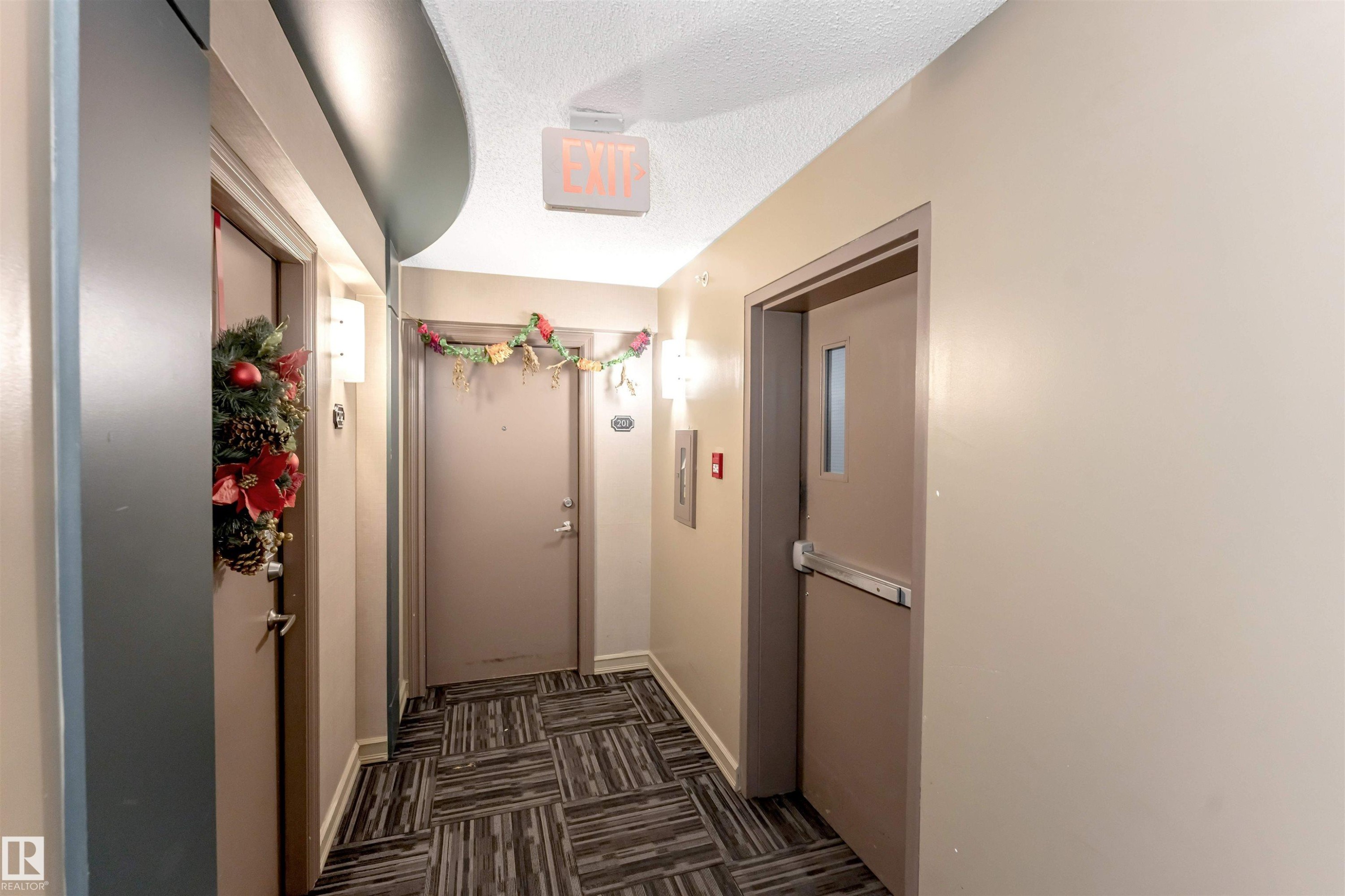 Hallway with a textured ceiling, dark colored carpet, and elevator - #201 4403 23 Street Nw, Edmonton, AB - Indoor Photo Showing Other Room