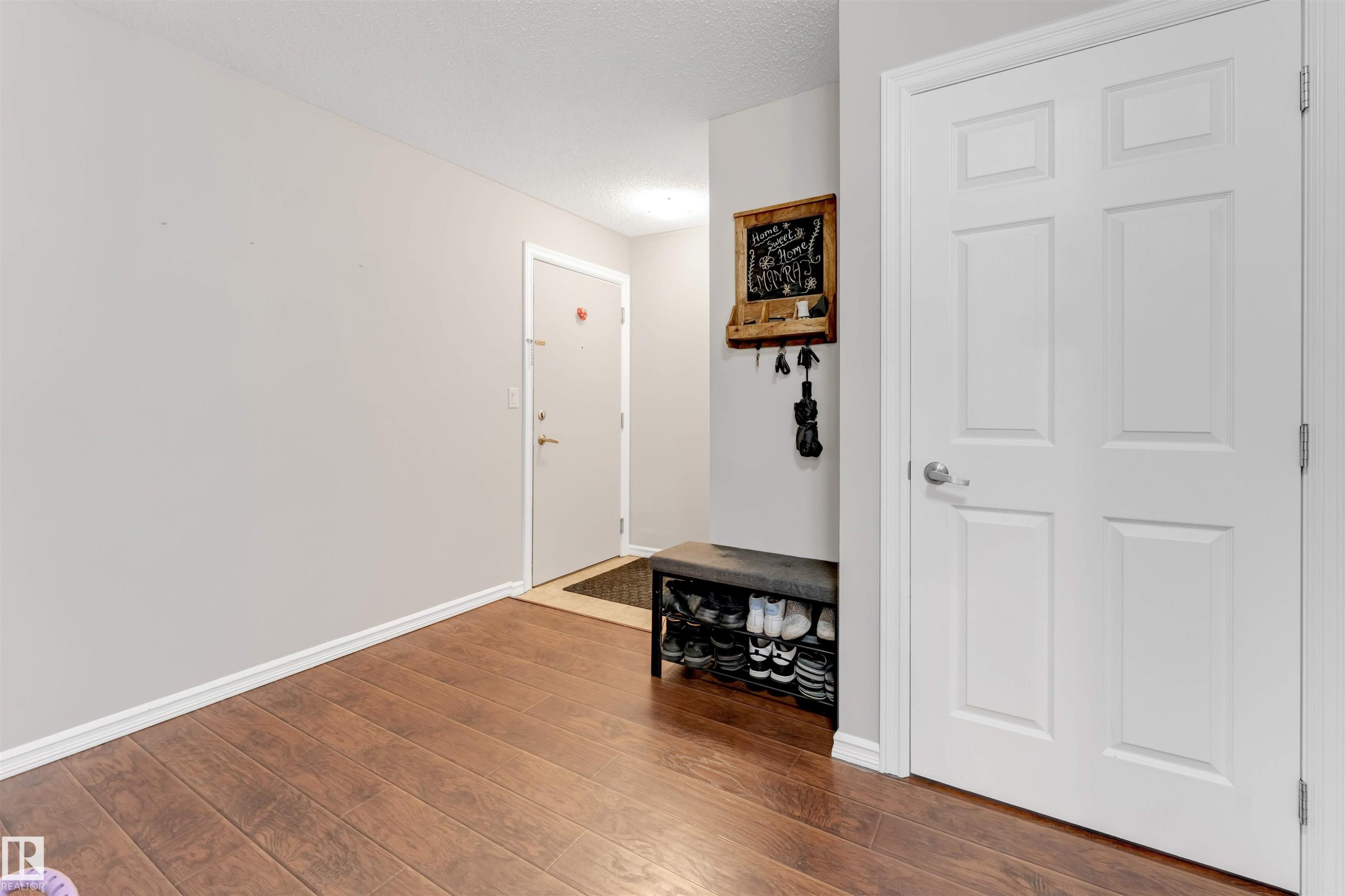 Foyer entrance with dark wood-style floors and a textured ceiling - #201 4403 23 Street Nw, Edmonton, AB - Indoor Photo Showing Other Room