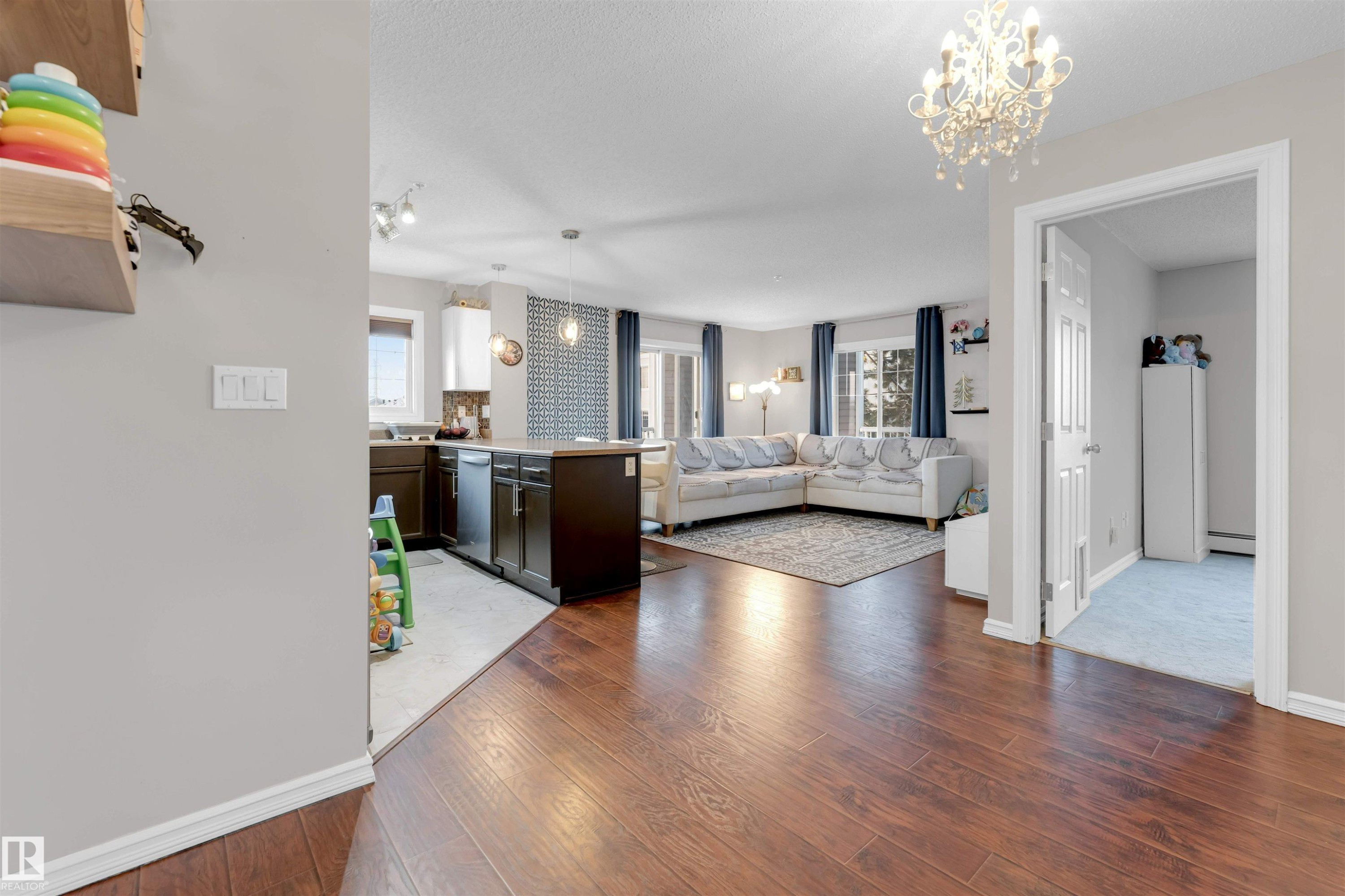 Bedroom with a chandelier, dark wood-style flooring, and baseboard heating - #201 4403 23 Street Nw, Edmonton, AB - Indoor