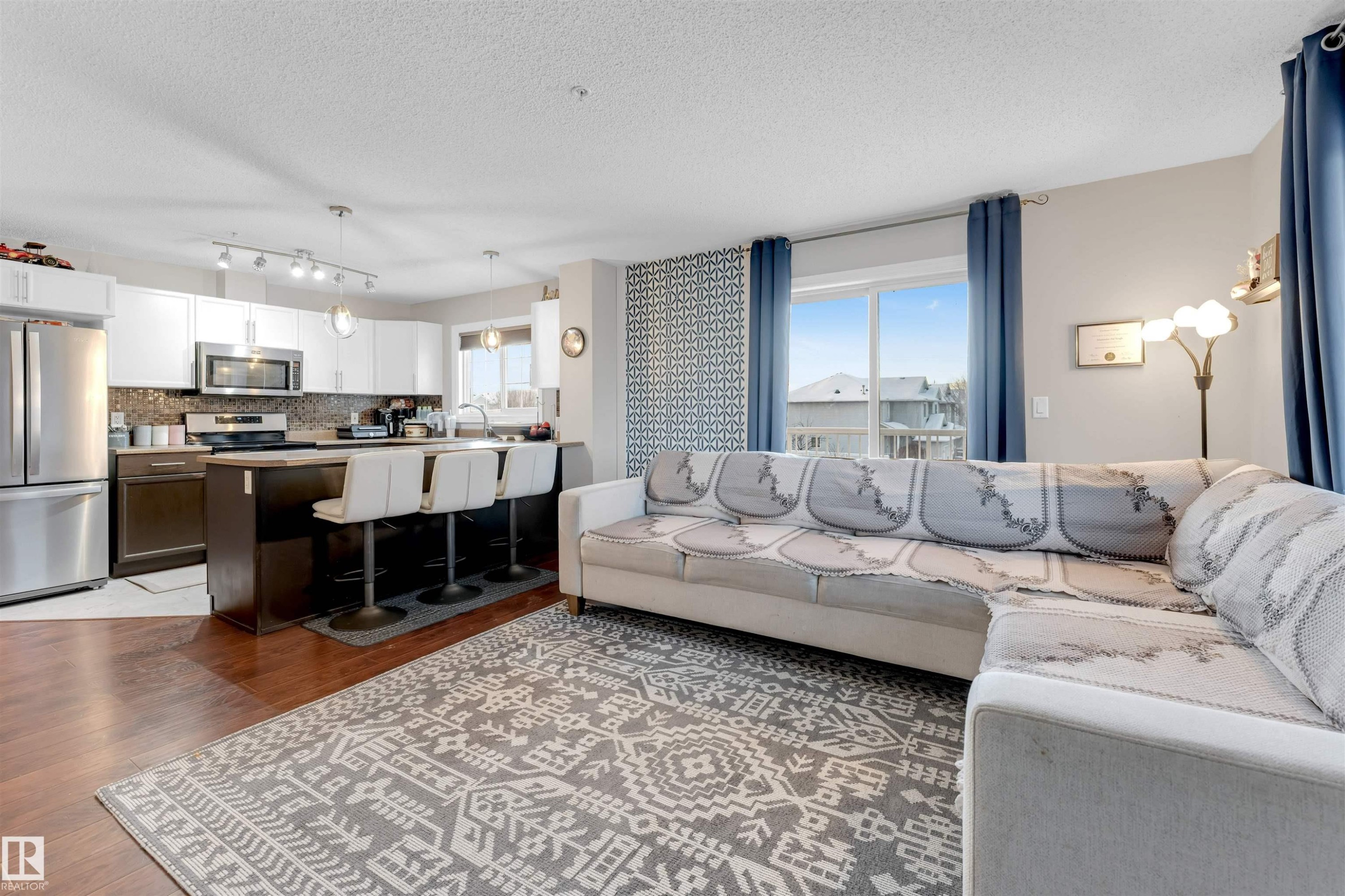 Living area with a textured ceiling and dark wood-style floors - #201 4403 23 Street Nw, Edmonton, AB - Indoor Photo Showing Living Room