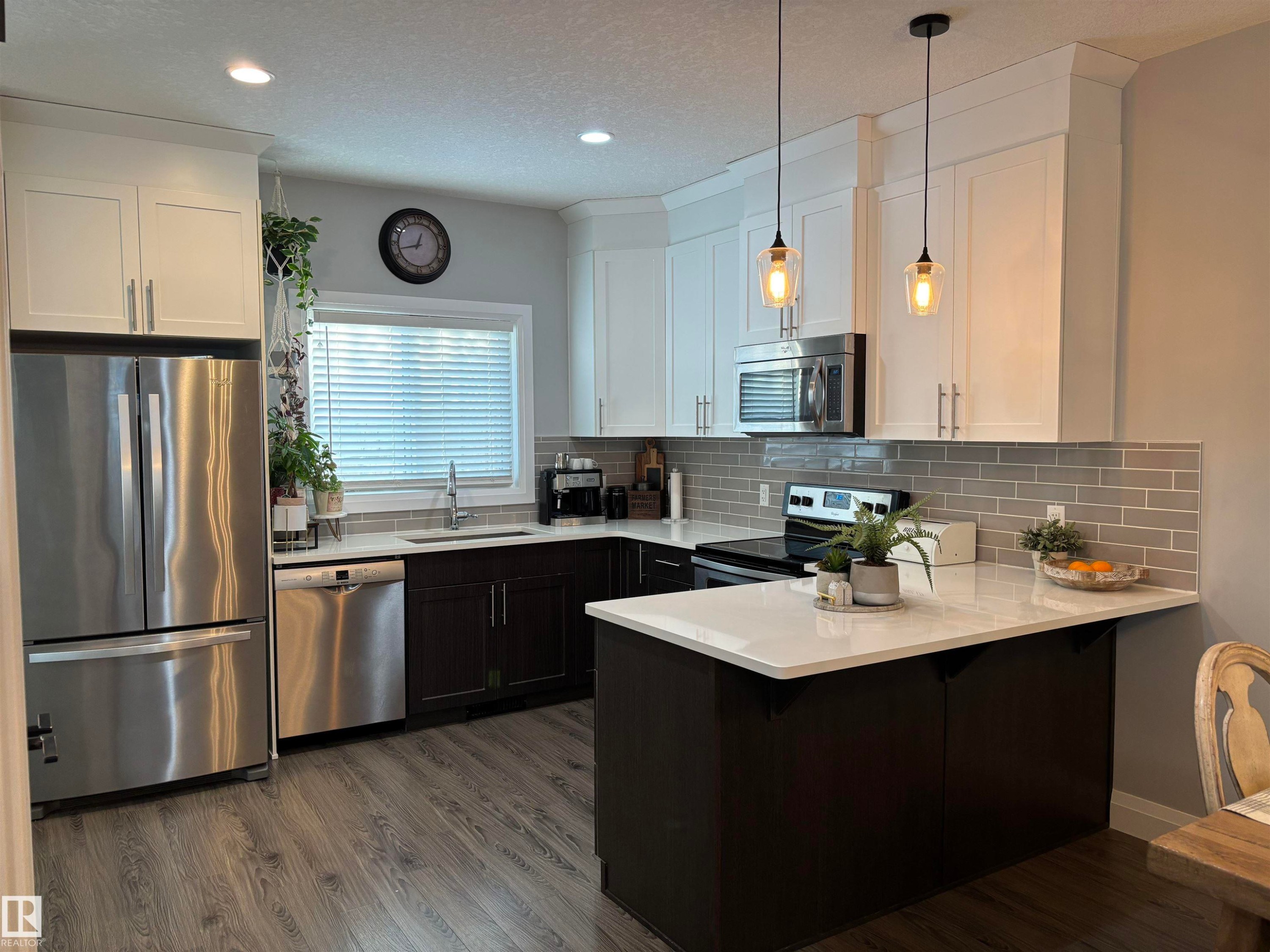 Kitchen featuring stainless steel appliances, white cabinets, a peninsula, a textured ceiling, and a breakfast bar - 25 Harrison Gate, Spruce Grove, AB - Indoor Photo Showing Kitchen With Upgraded Kitchen
