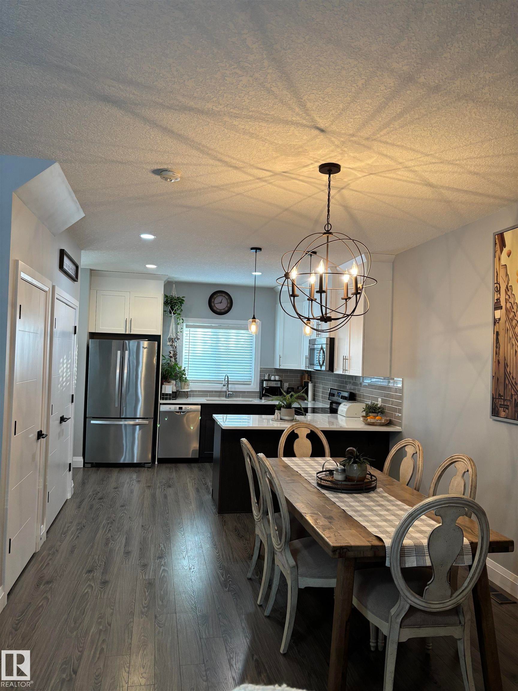 Dining room with dark wood-style flooring and a chandelier - 25 Harrison Gate, Spruce Grove, AB - Indoor Photo Showing Dining Room