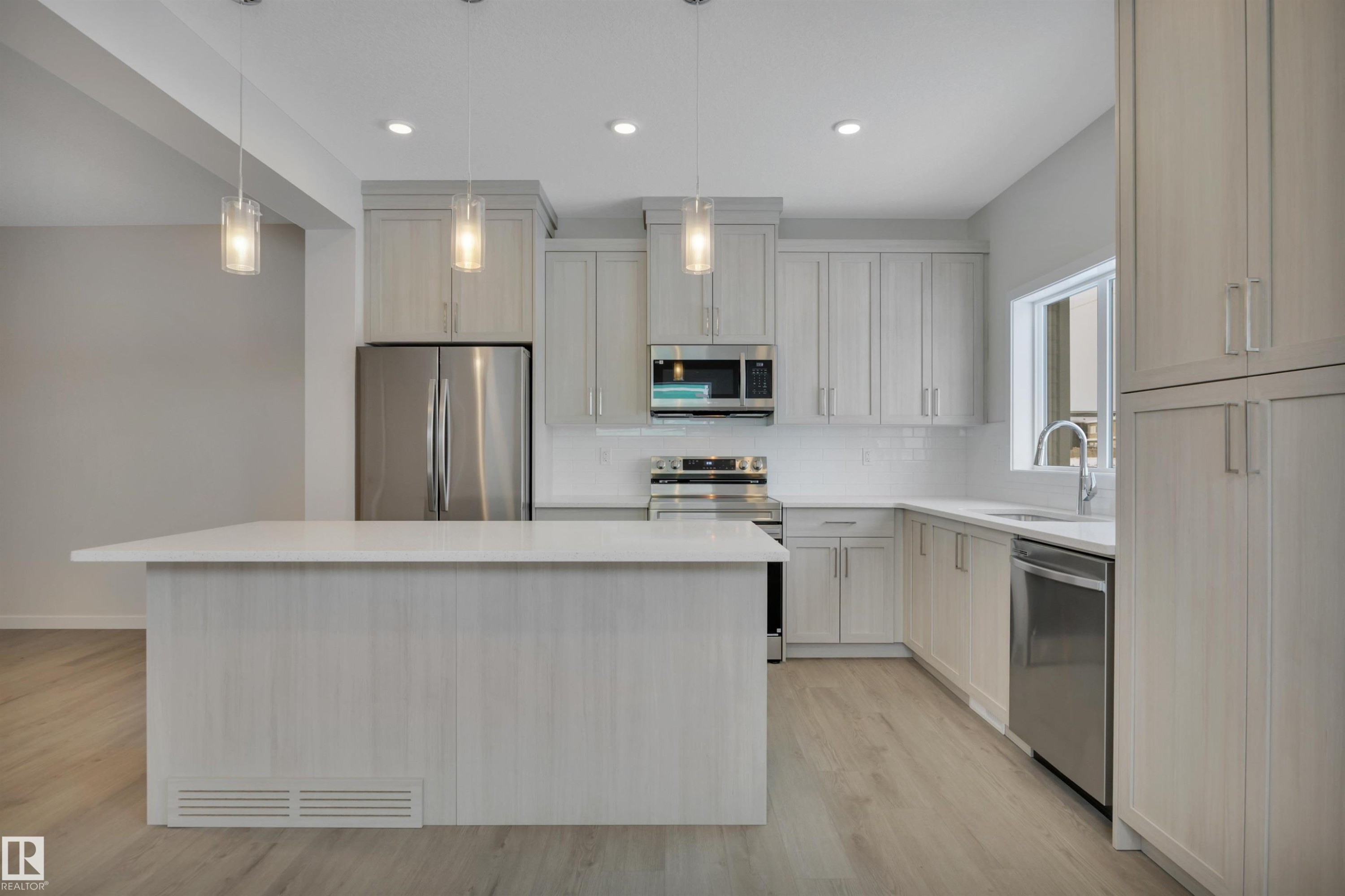 Kitchen with appliances with stainless steel finishes, a center island, pendant lighting, tasteful backsplash, and light wood-style flooring - 5742 Hawthorn Common, Edmonton, AB - Indoor Photo Showing Kitchen With Stainless Steel Kitchen With Upgraded Kitchen