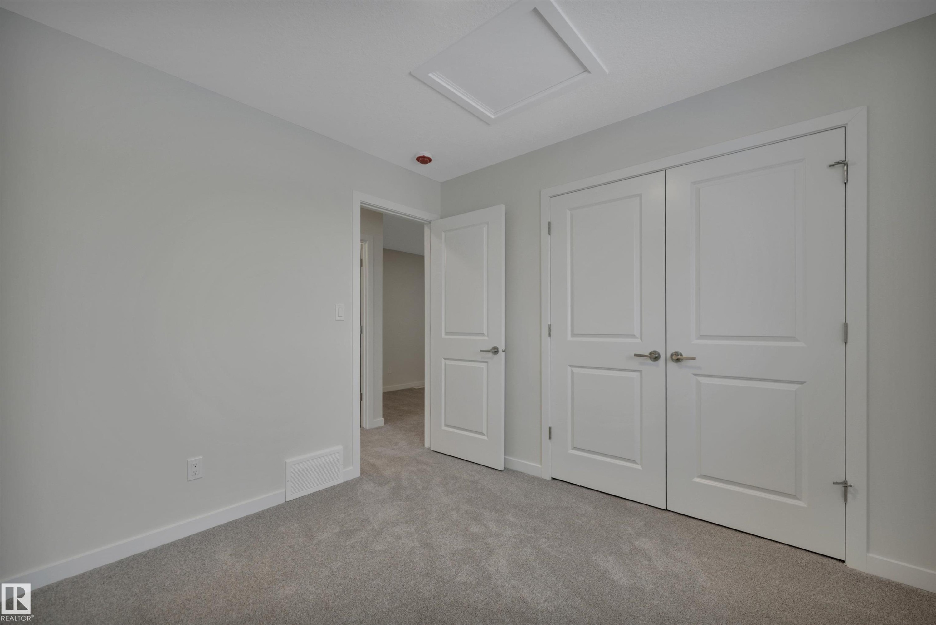 Unfurnished bedroom featuring attic access, carpet, and a closet - 5742 Hawthorn Common, Edmonton, AB - Indoor Photo Showing Other Room