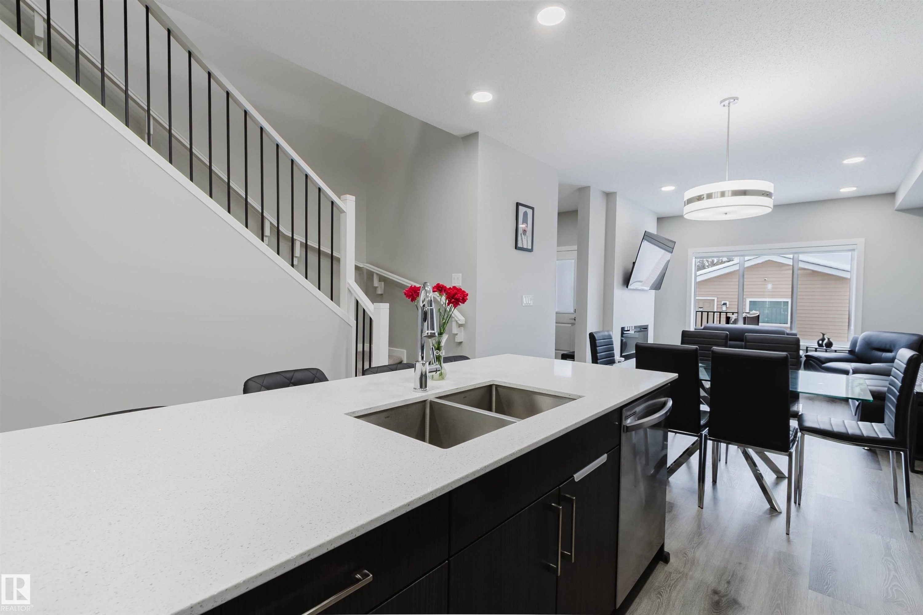 Kitchen featuring dark cabinetry, hanging light fixtures, light stone counters, recessed lighting, and dishwasher - 343 Edgemont Drive, Edmonton, AB - Indoor Photo Showing Kitchen With Double Sink