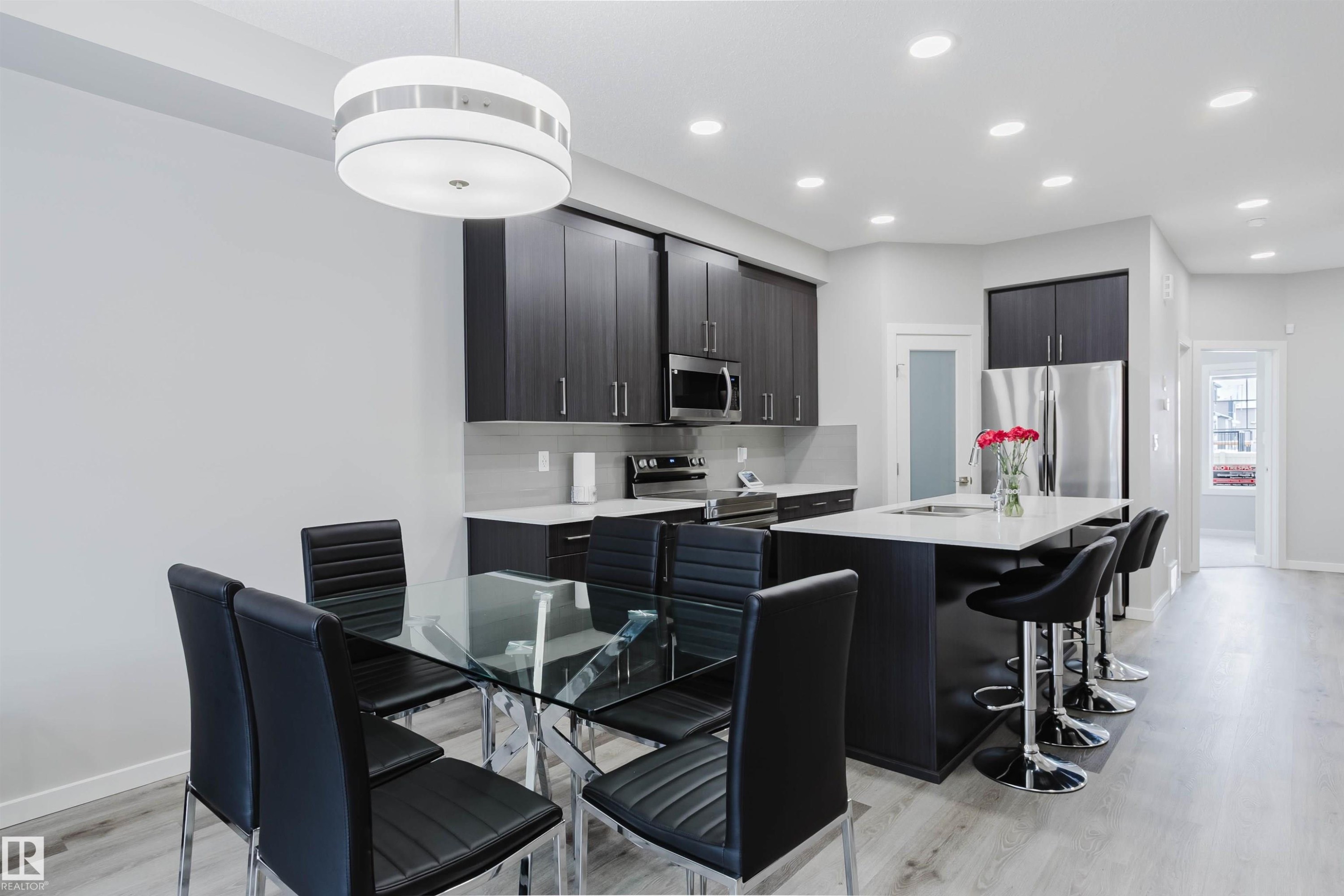 Kitchen with stainless steel appliances, an island with sink, a kitchen breakfast bar, pendant lighting, and dark cabinetry - 343 Edgemont Drive, Edmonton, AB - Indoor