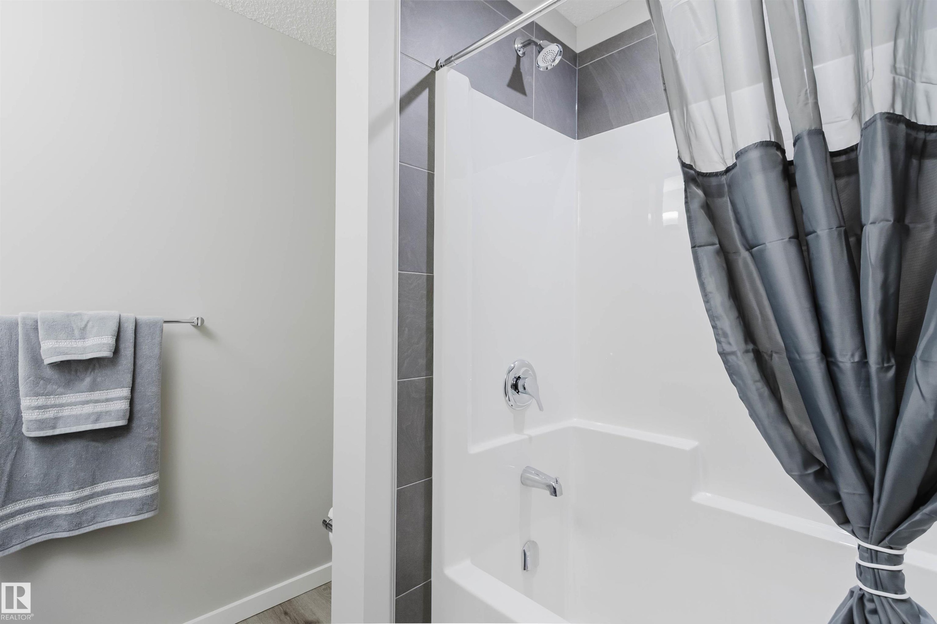 Full bath featuring shower / bath combo, a textured ceiling, and wood finished floors - 343 Edgemont Drive, Edmonton, AB - Indoor Photo Showing Bathroom