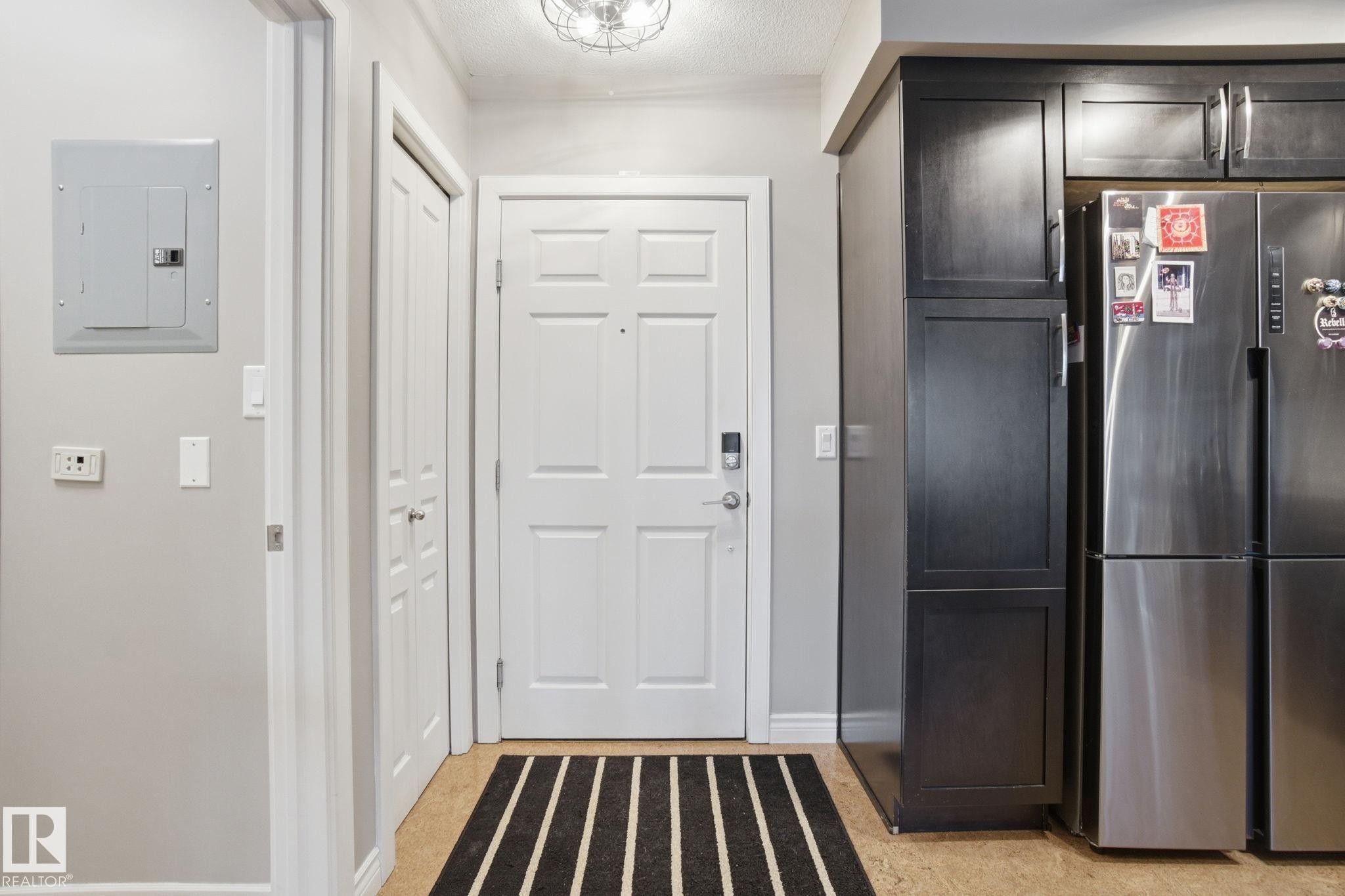 Kitchen with freestanding refrigerator, electric panel, and dark brown cabinetry - 301 9603 98 Avenue, Edmonton, AB - Indoor Photo Showing Other Room