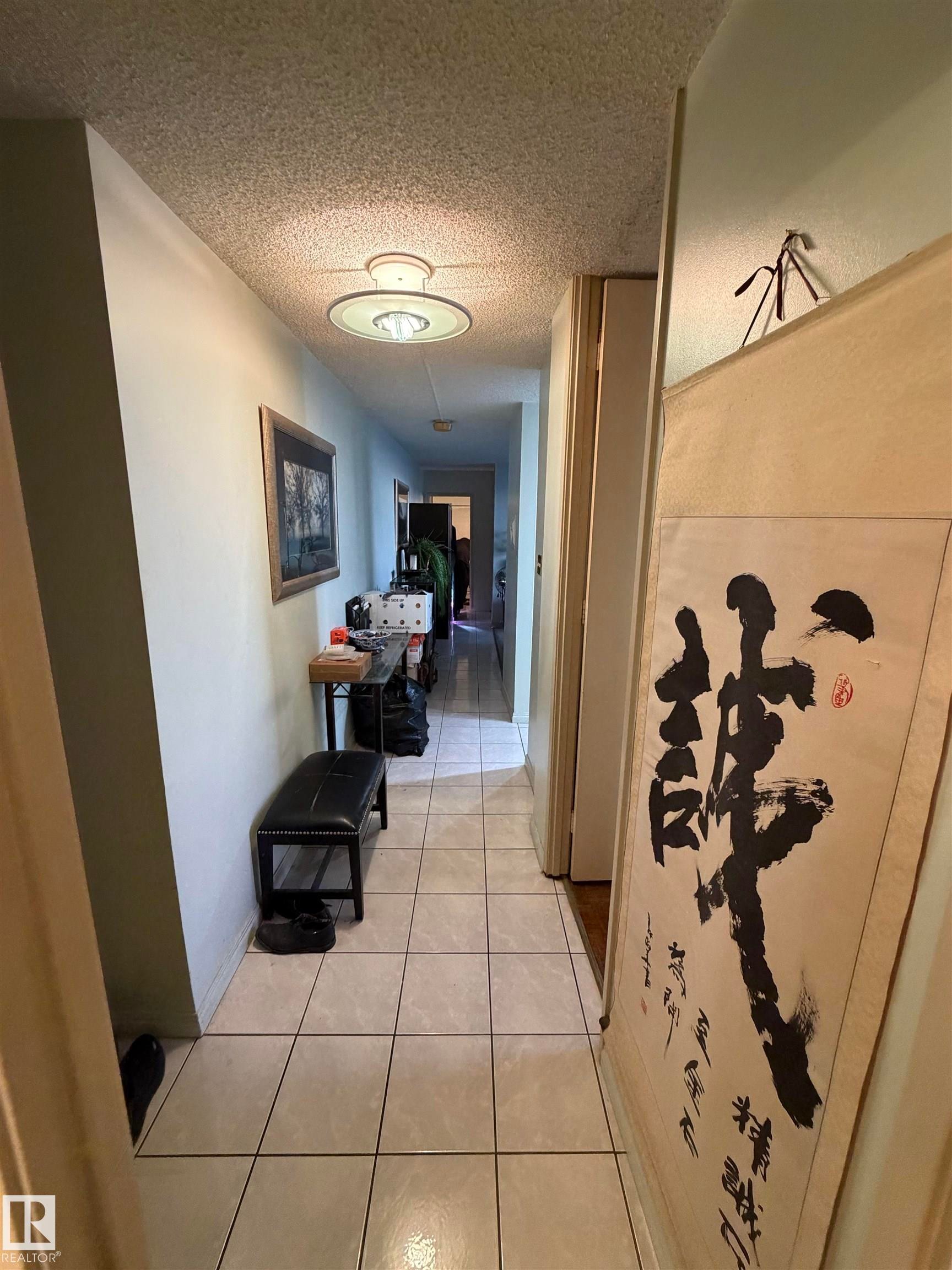 Hallway featuring light tile patterned flooring and a textured ceiling - 1506 10883 Saskatchewan Dr, Edmonton, AB - Indoor Photo Showing Other Room