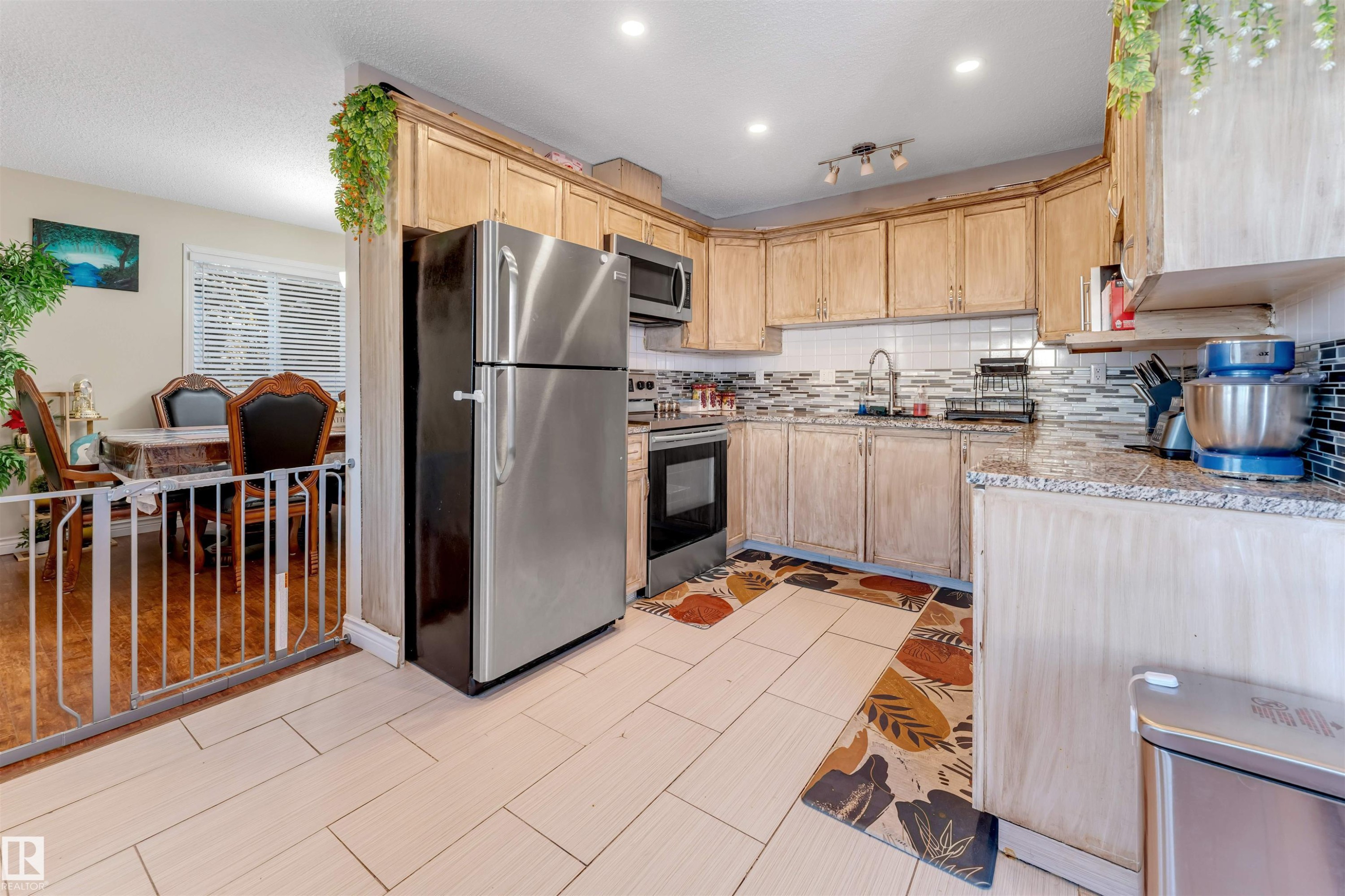 Kitchen with light brown cabinets, stainless steel appliances, backsplash, and light stone countertops - 18404 97A Avenue, Edmonton, AB - Indoor Photo Showing Kitchen