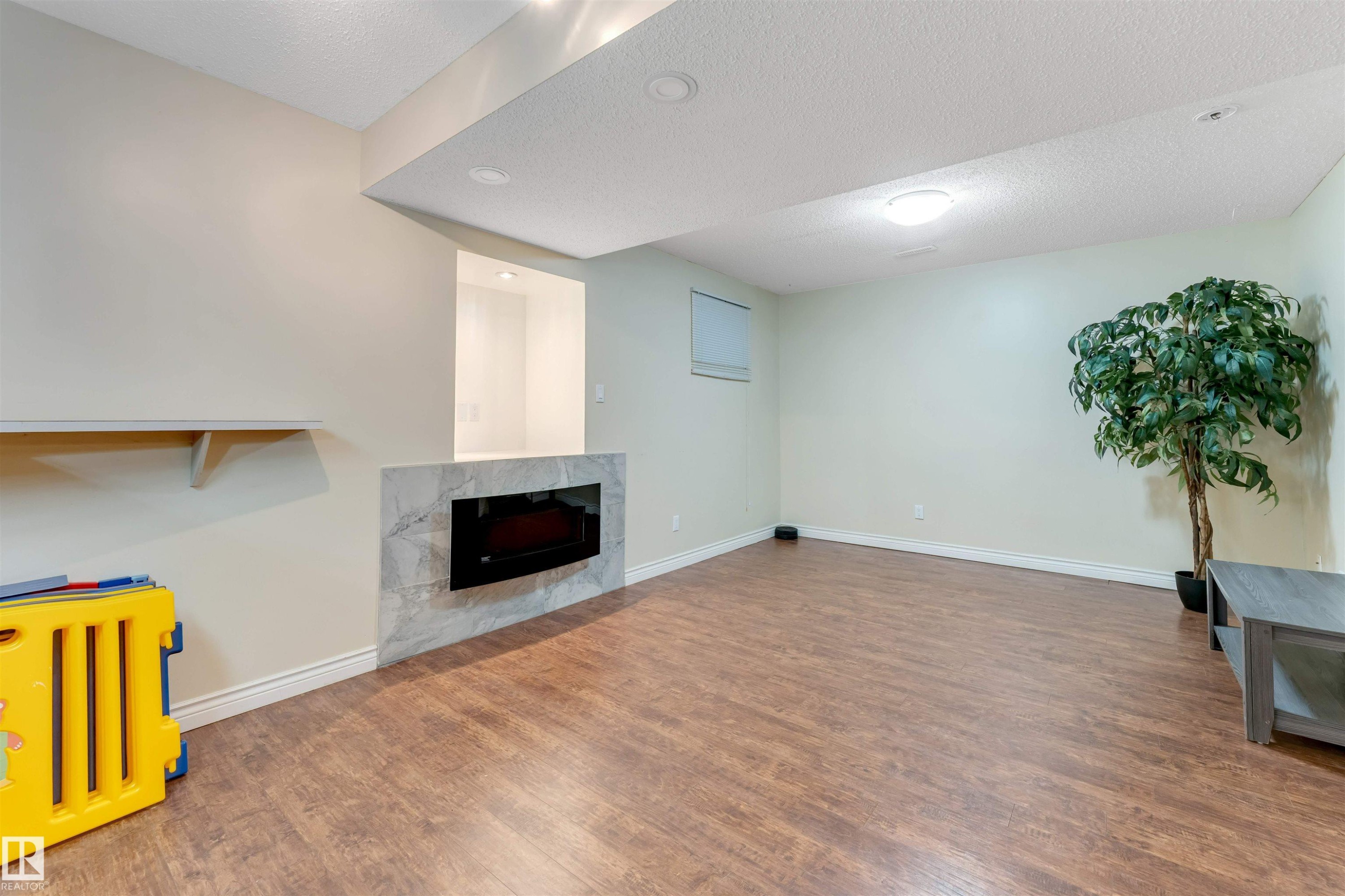 Unfurnished living room featuring a premium fireplace, wood finished floors, and a textured ceiling - 18404 97A Avenue, Edmonton, AB - Indoor