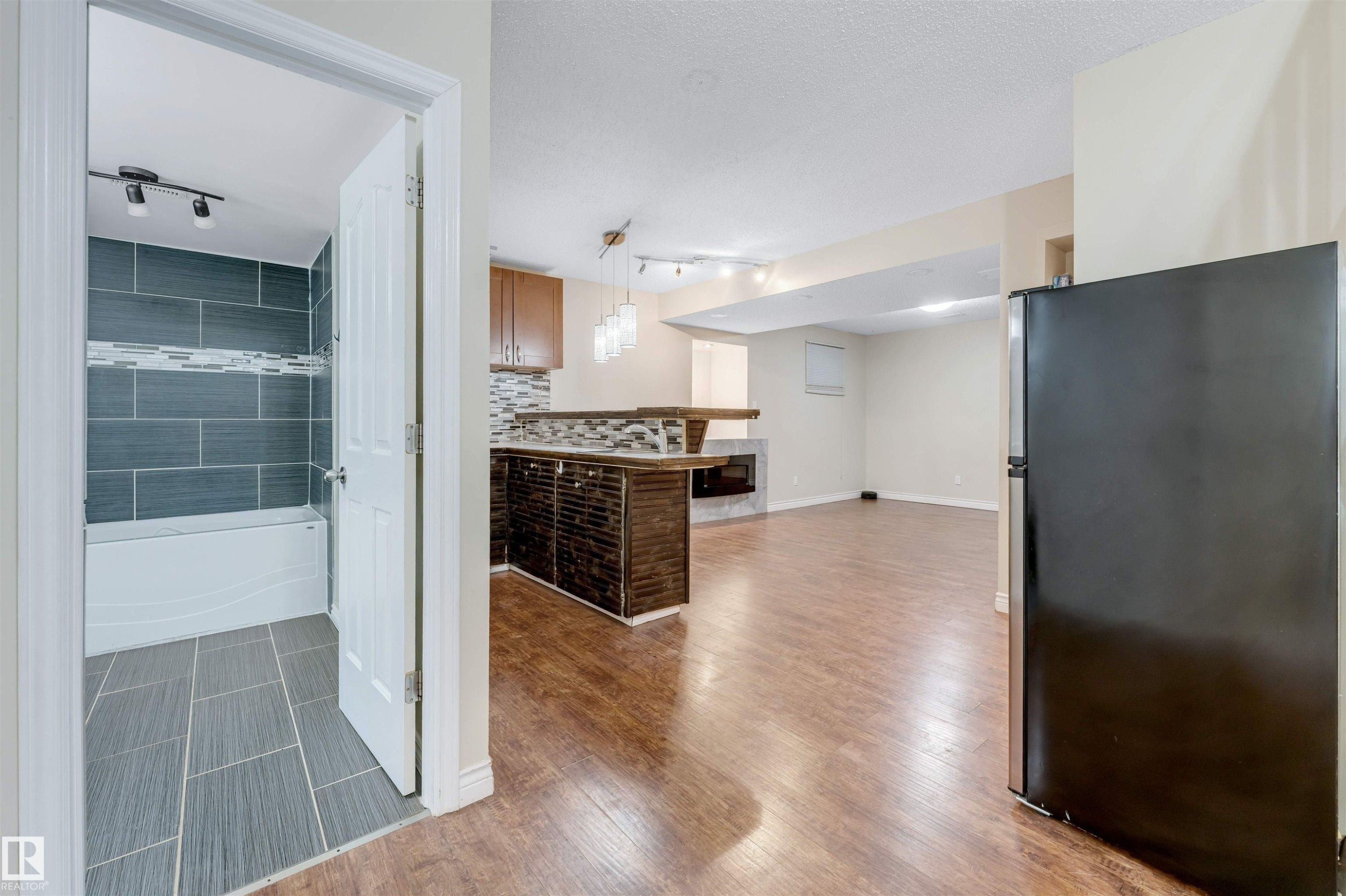 Kitchen featuring freestanding refrigerator, hanging light fixtures, rail lighting, and dark wood-style floors - 18404 97A Avenue, Edmonton, AB - Indoor