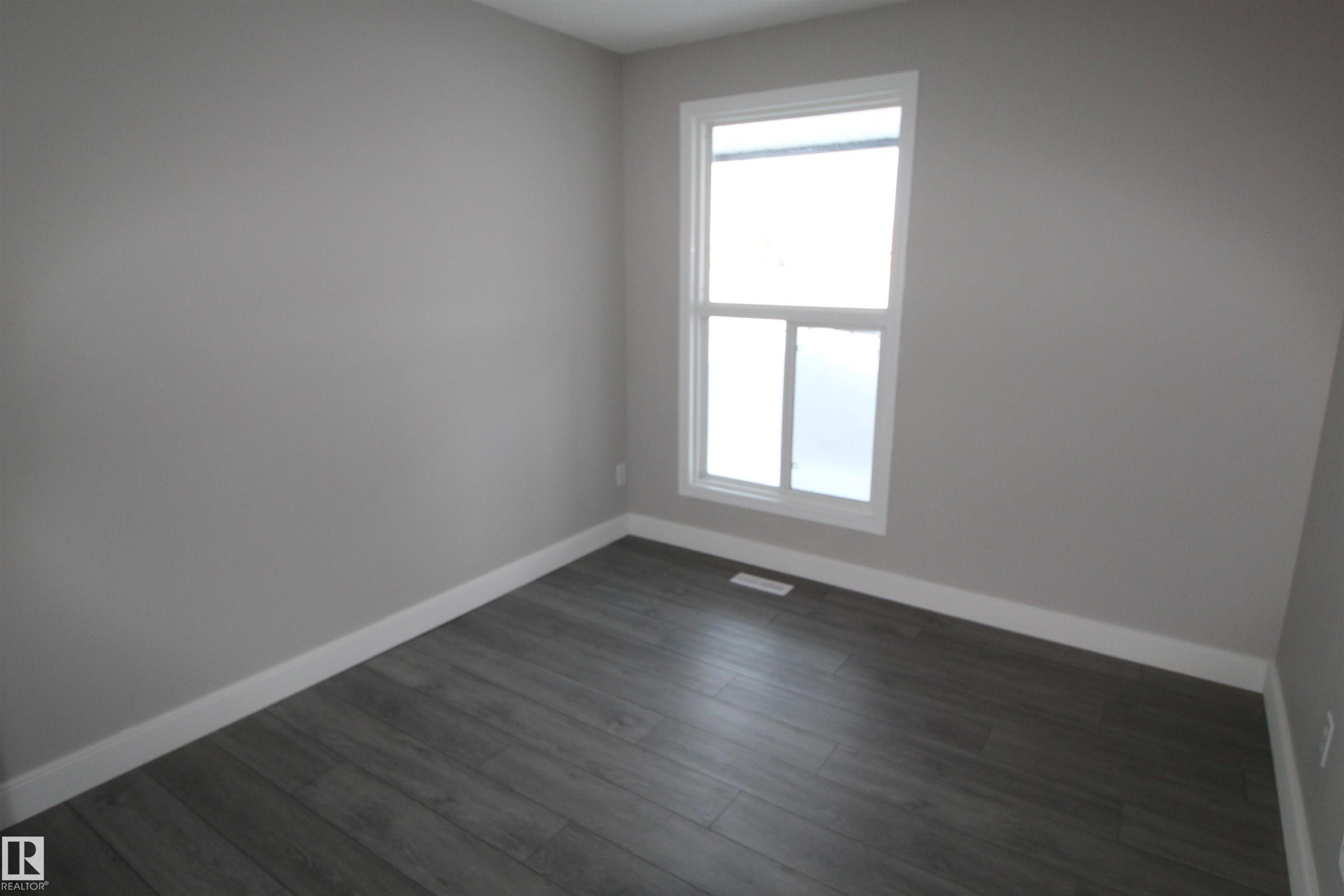 Empty room with baseboards and dark wood finished floors - 53 14620 26 Street, Edmonton, AB - Indoor Photo Showing Other Room