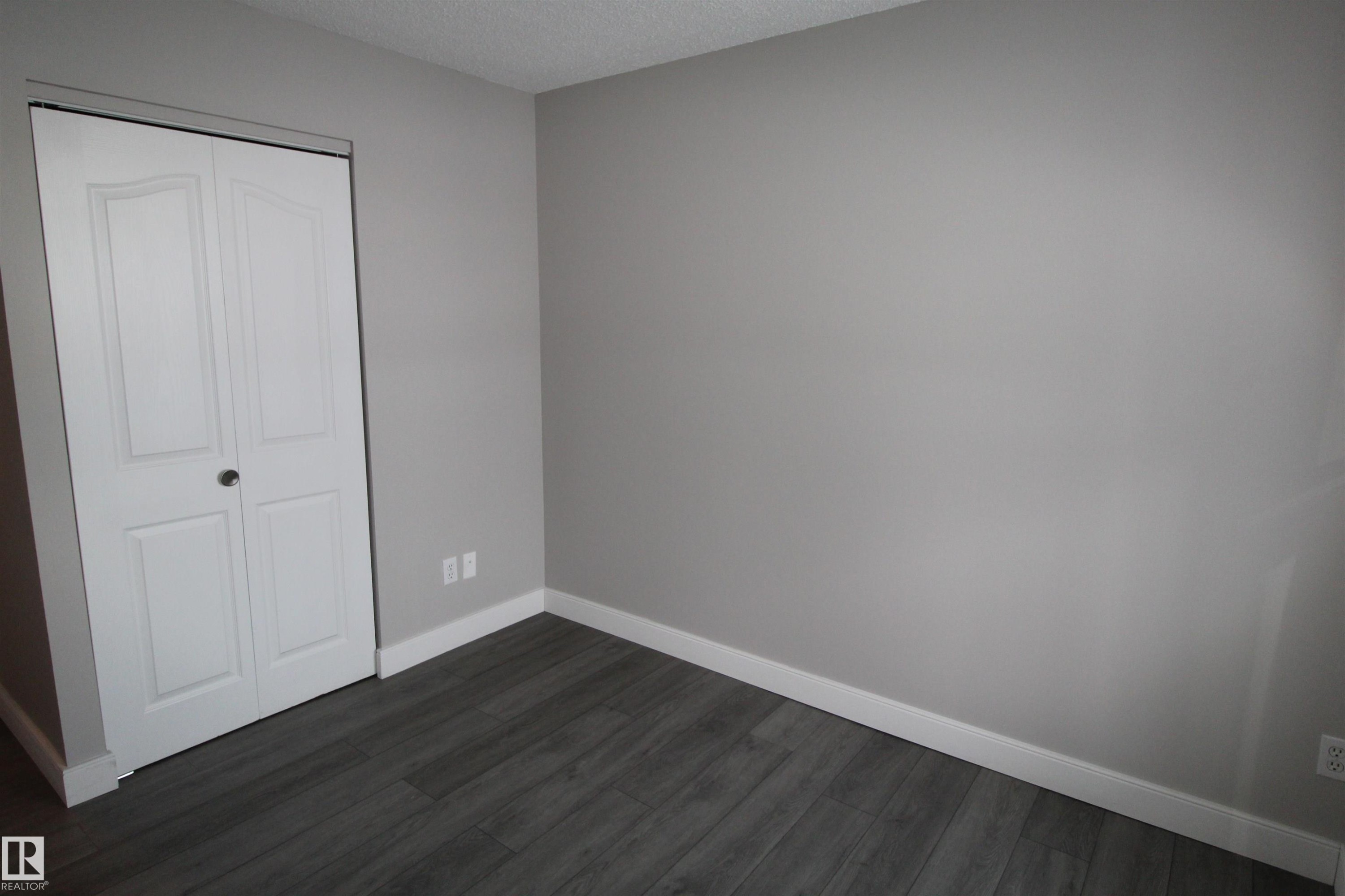 Unfurnished bedroom with dark wood-type flooring, a closet, and a textured ceiling - 53 14620 26 Street, Edmonton, AB - Indoor Photo Showing Other Room