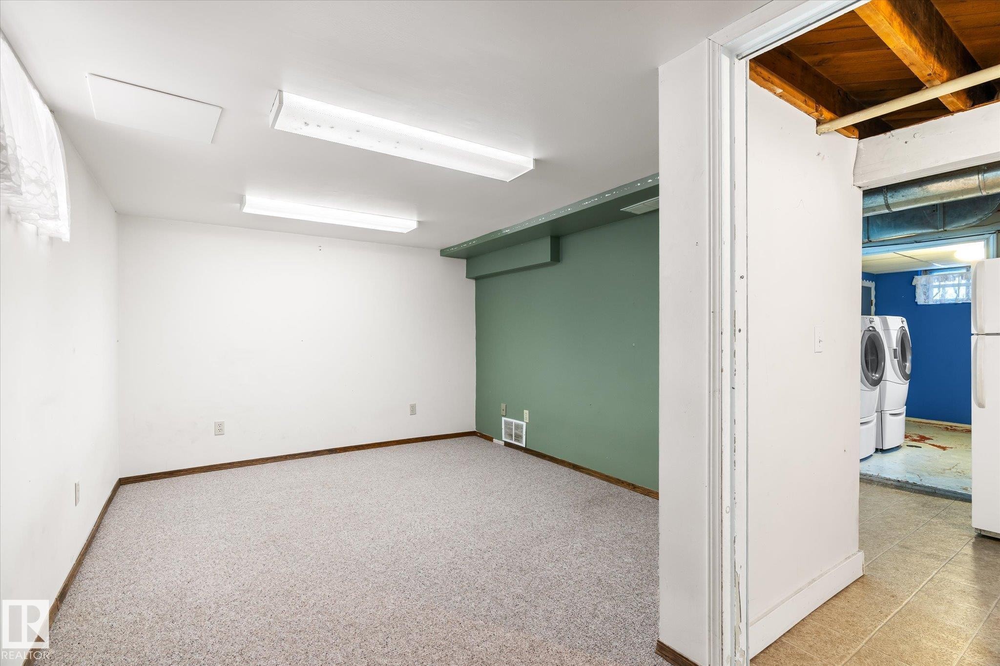 Below grade area with freestanding refrigerator, washer and clothes dryer, and light carpet - 10429 143 Street, Edmonton, AB - Indoor