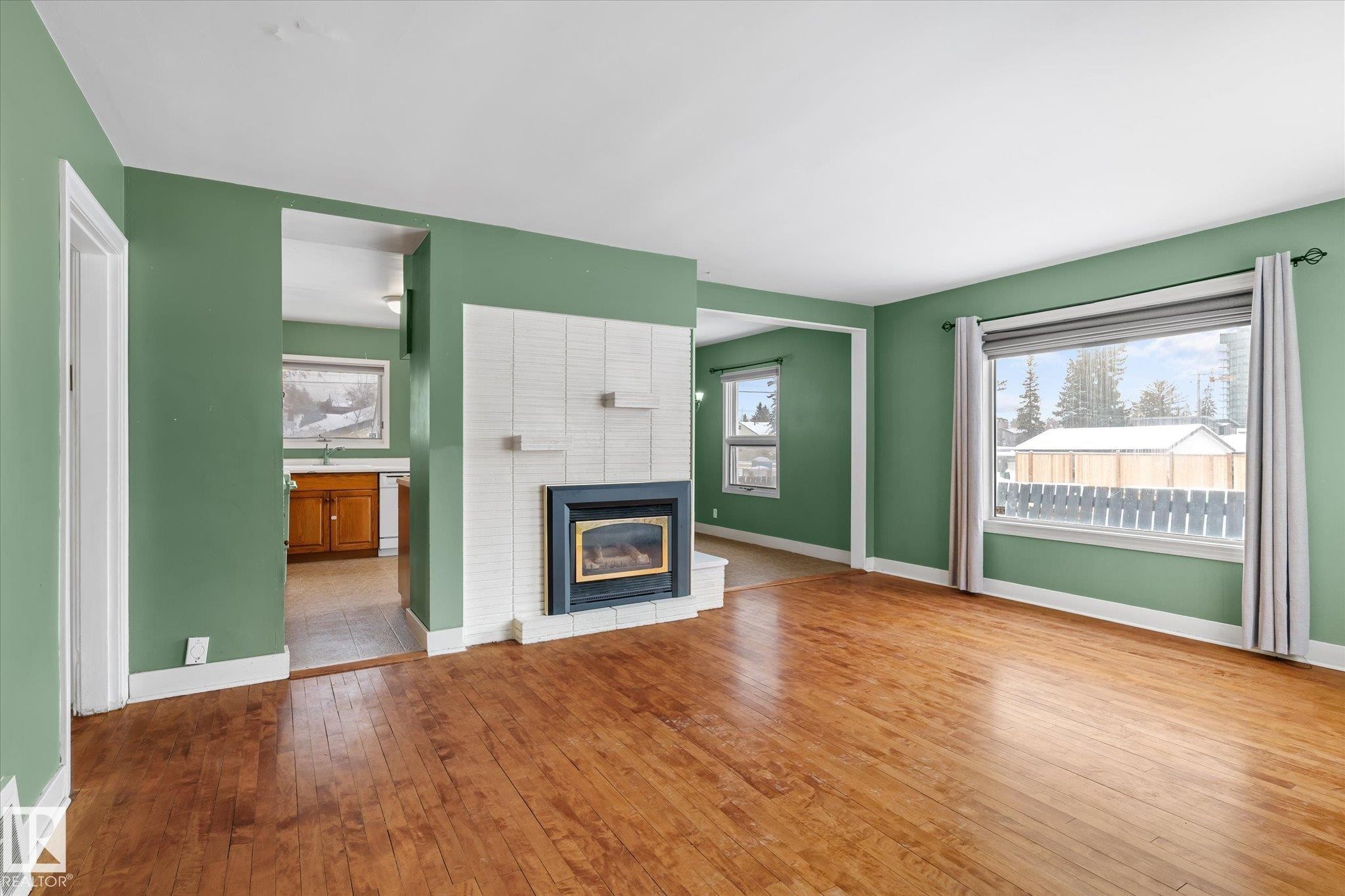 Unfurnished living room featuring a brick fireplace and wood-type flooring - 10429 143 Street, Edmonton, AB - Indoor Photo Showing Living Room With Fireplace