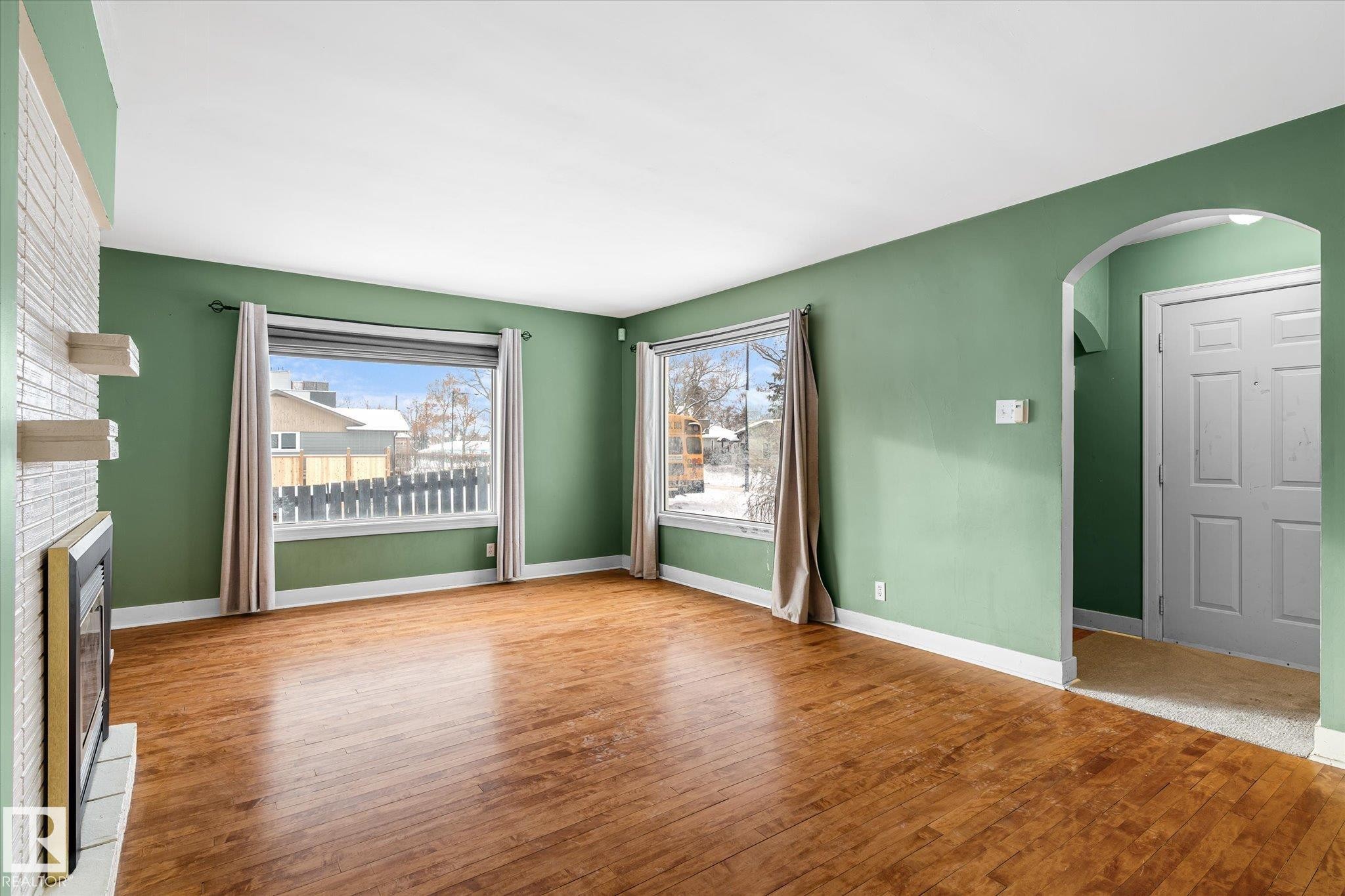 Unfurnished living room with hardwood / wood-style floors, arched walkways, and a fireplace - 10429 143 Street, Edmonton, AB - Indoor With Fireplace