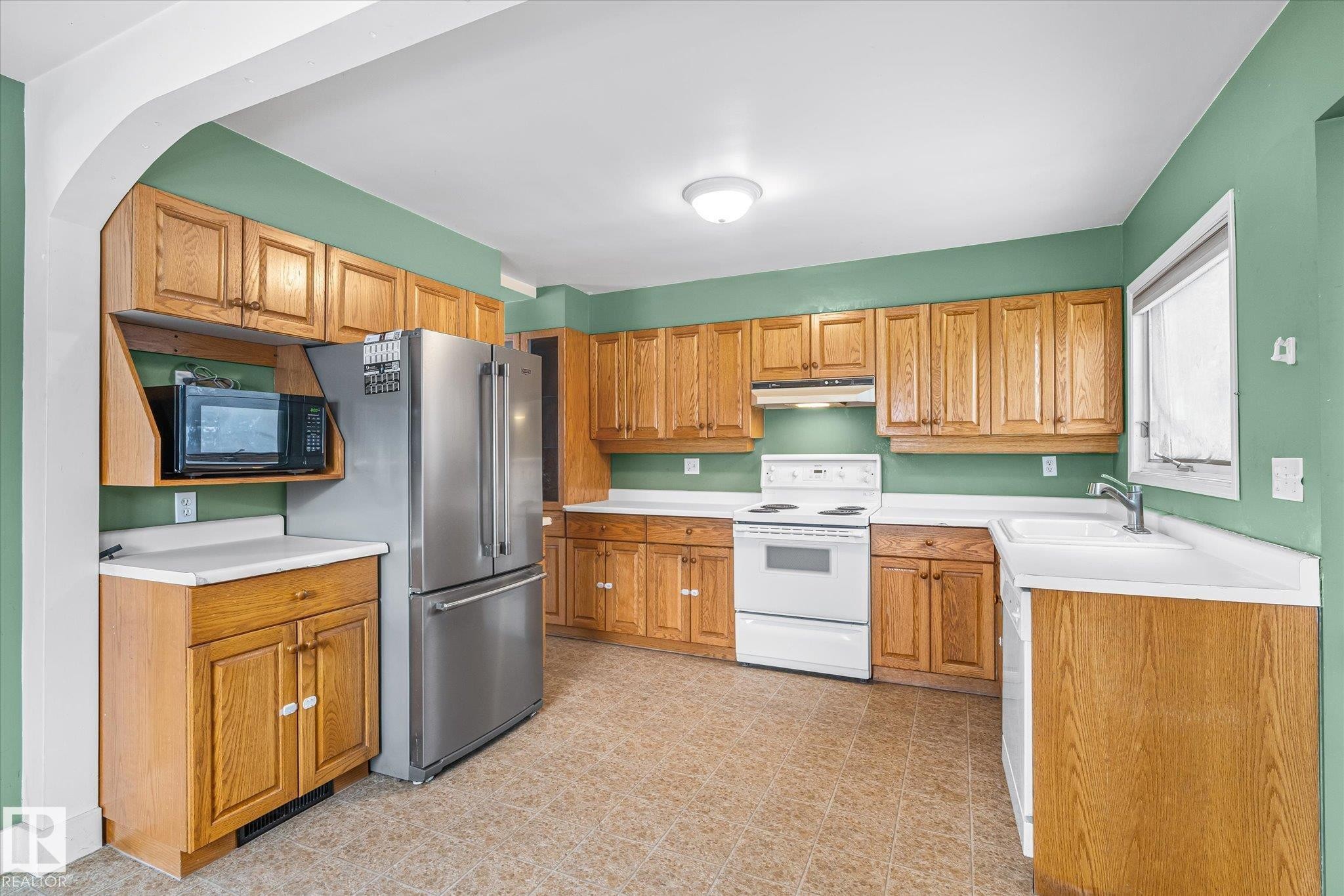 Kitchen with white electric range, light countertops, high end refrigerator, light flooring, and black microwave - 10429 143 Street, Edmonton, AB - Indoor Photo Showing Kitchen