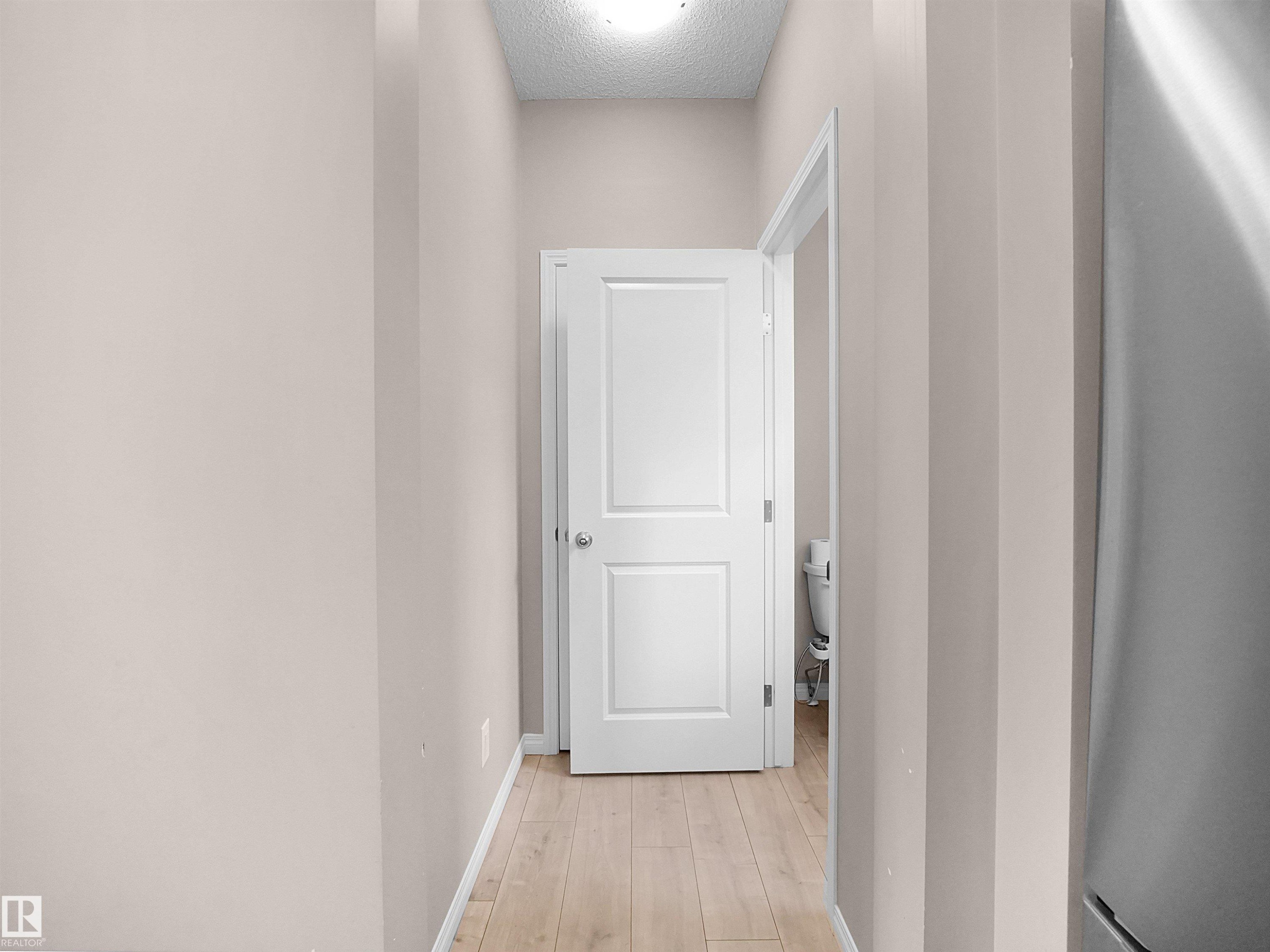Hall with light wood-type flooring and a textured ceiling - 2080 Wonnacott Way, Edmonton, AB - Indoor Photo Showing Other Room