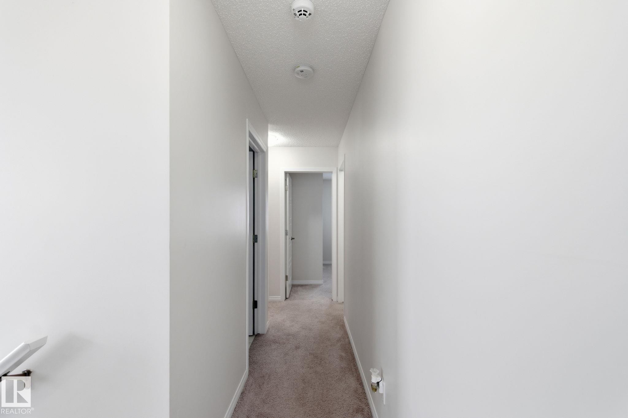 Hallway featuring light colored carpet and a textured ceiling - 1511 Secord Rd, Edmonton, AB - Indoor Photo Showing Other Room
