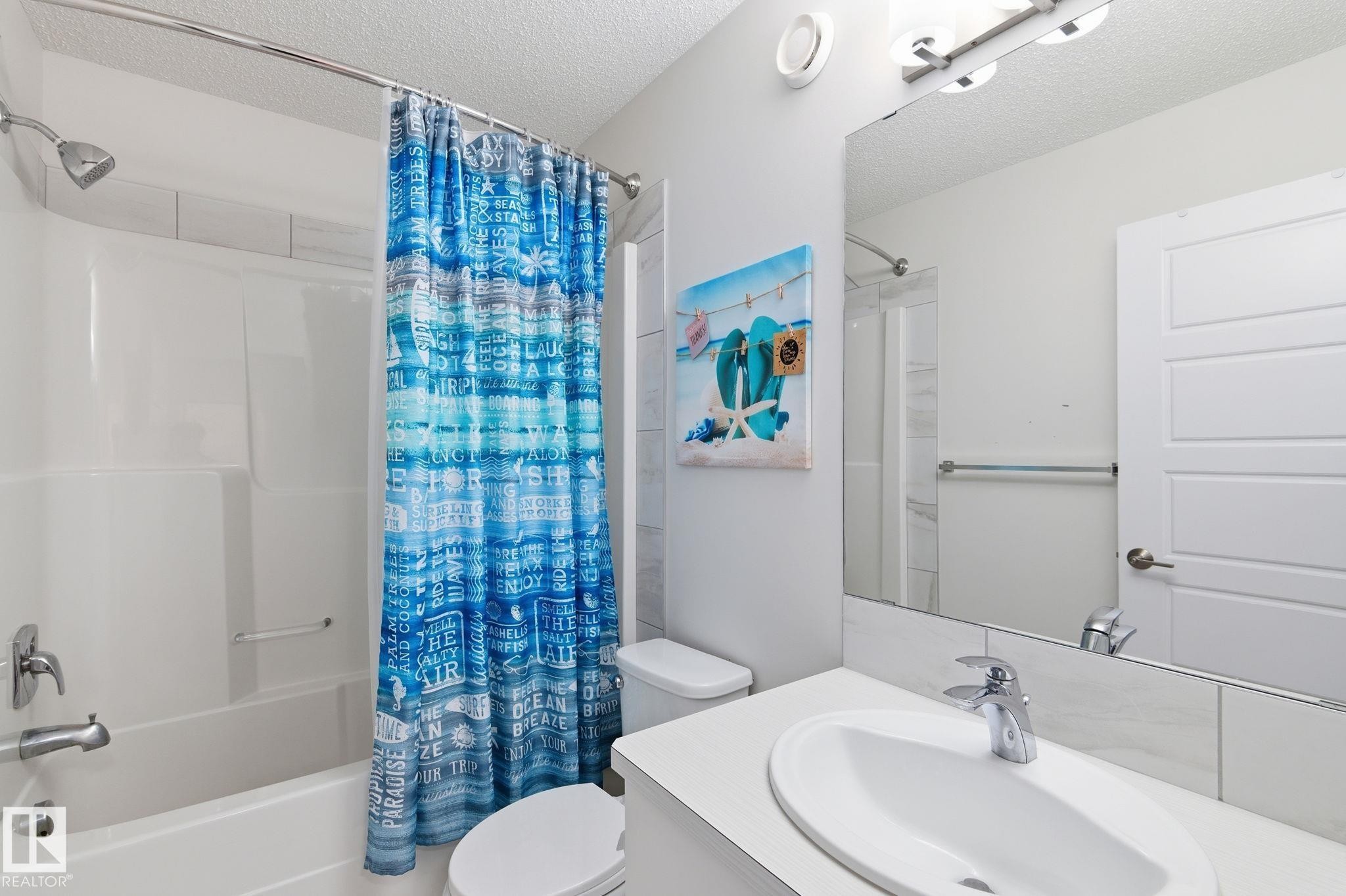 Bathroom with a textured ceiling, vanity, and shower / bath combination with curtain - 1511 Secord Rd, Edmonton, AB - Indoor Photo Showing Bathroom
