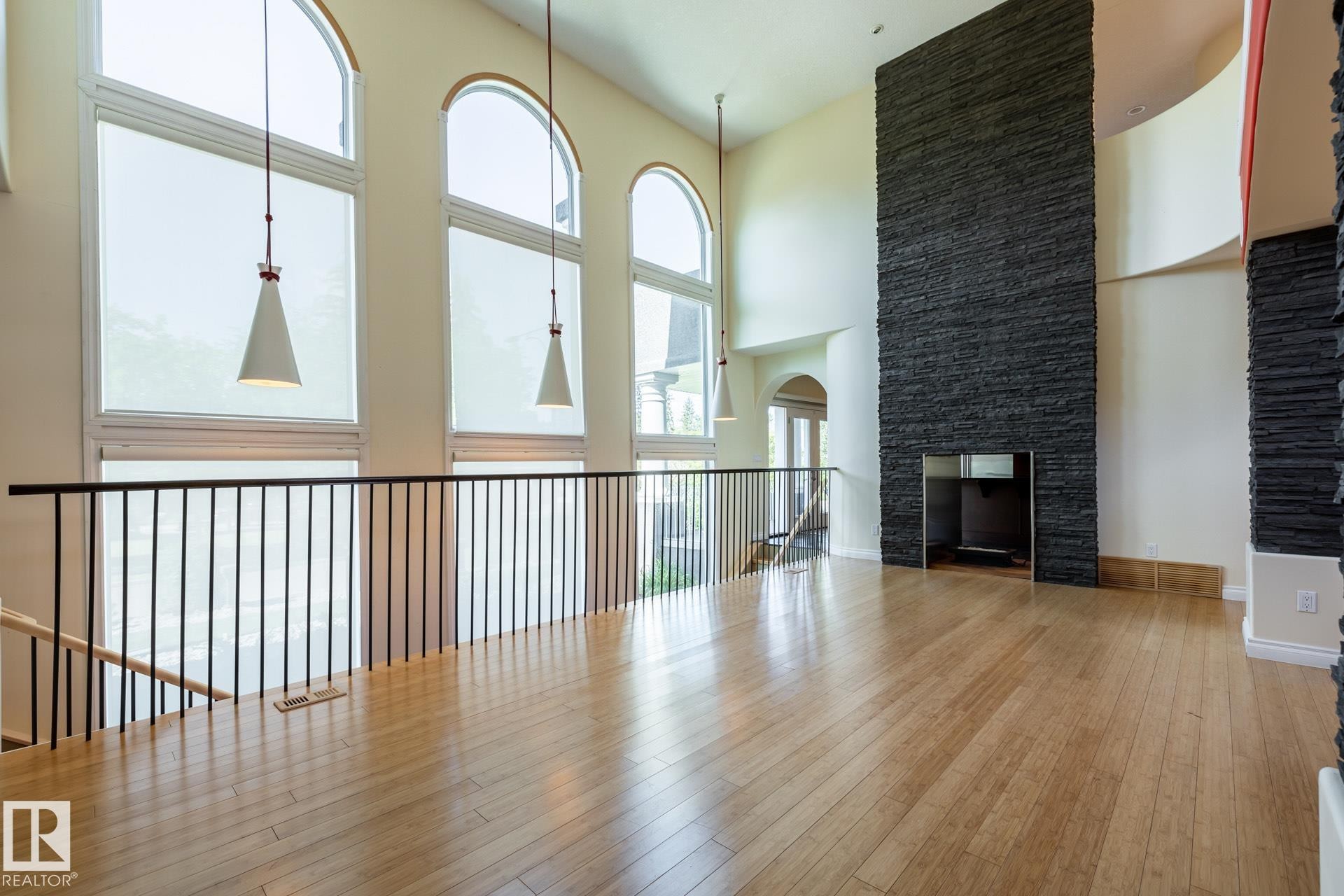 Unfurnished living room featuring hardwood / wood-style floors and a towering ceiling - 12428 103 Avenue Nw, Edmonton, AB - Indoor Photo Showing Other Room With Fireplace