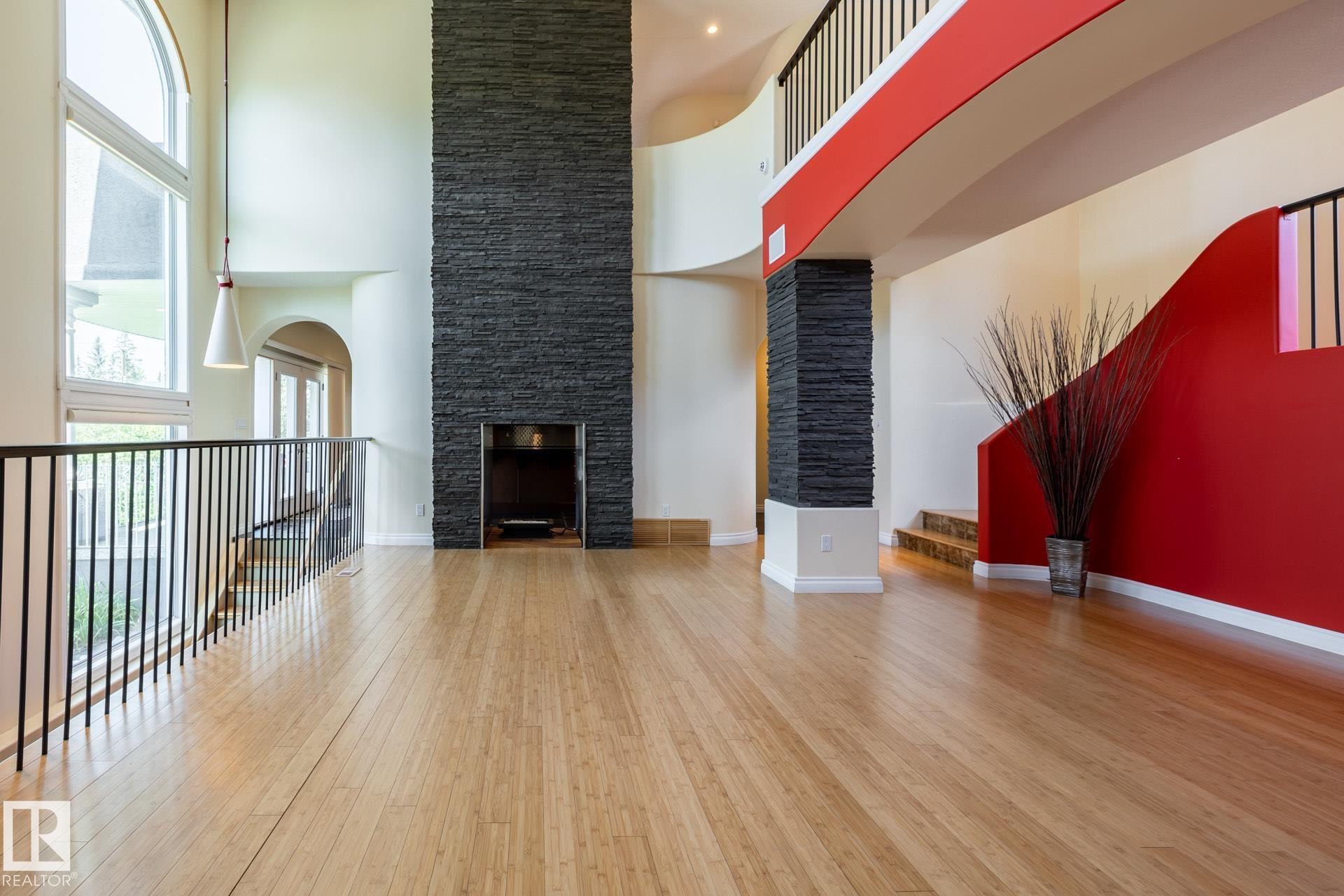 Unfurnished living room featuring light wood finished floors, a towering ceiling, and arched walkways - 12428 103 Avenue Nw, Edmonton, AB - Indoor With Fireplace