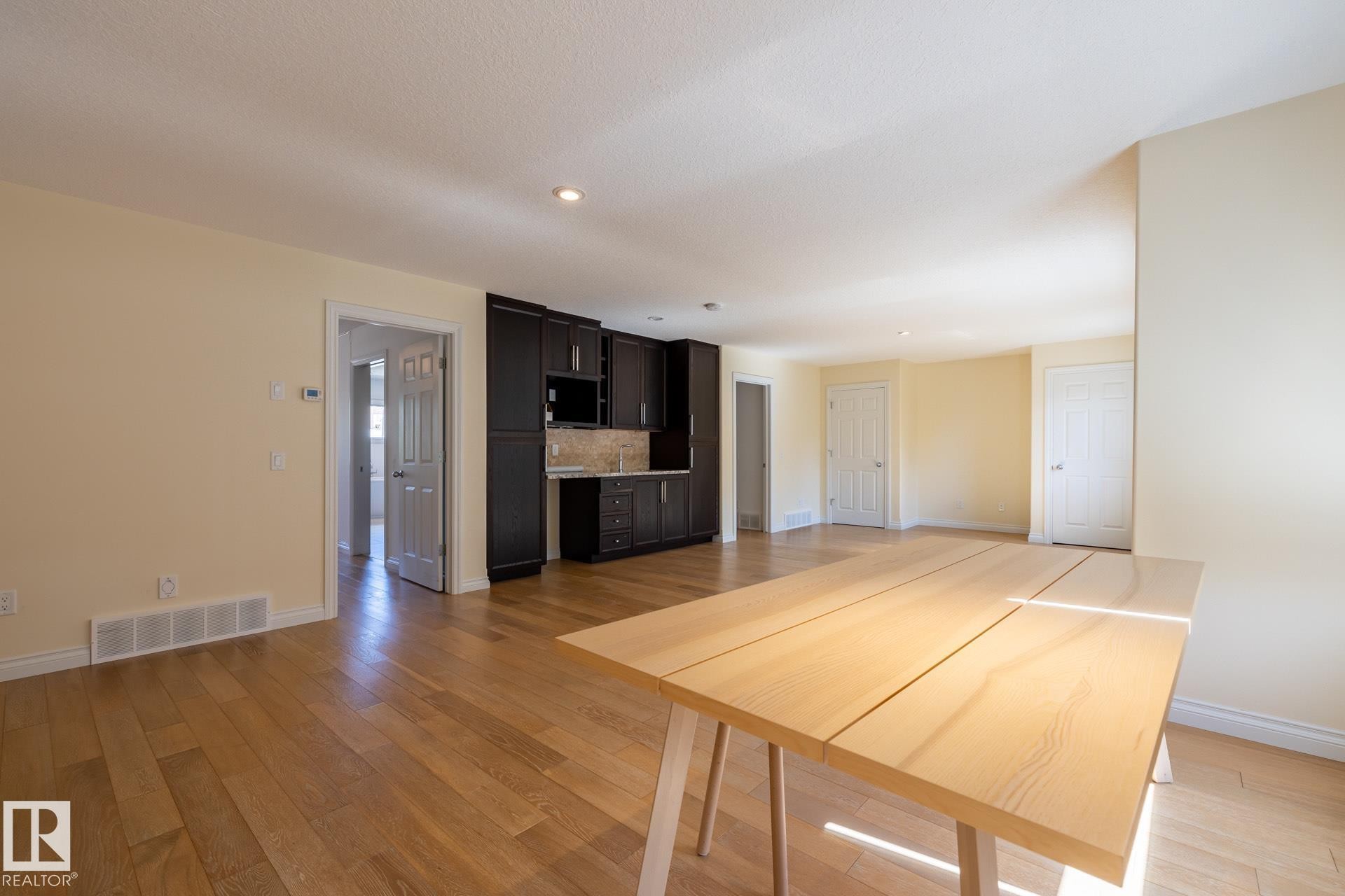 Kitchen featuring light countertops, light wood-type flooring, dark brown cabinets, tasteful backsplash, and recessed lighting - 12428 103 Avenue Nw, Edmonton, AB - Indoor Photo Showing Other Room