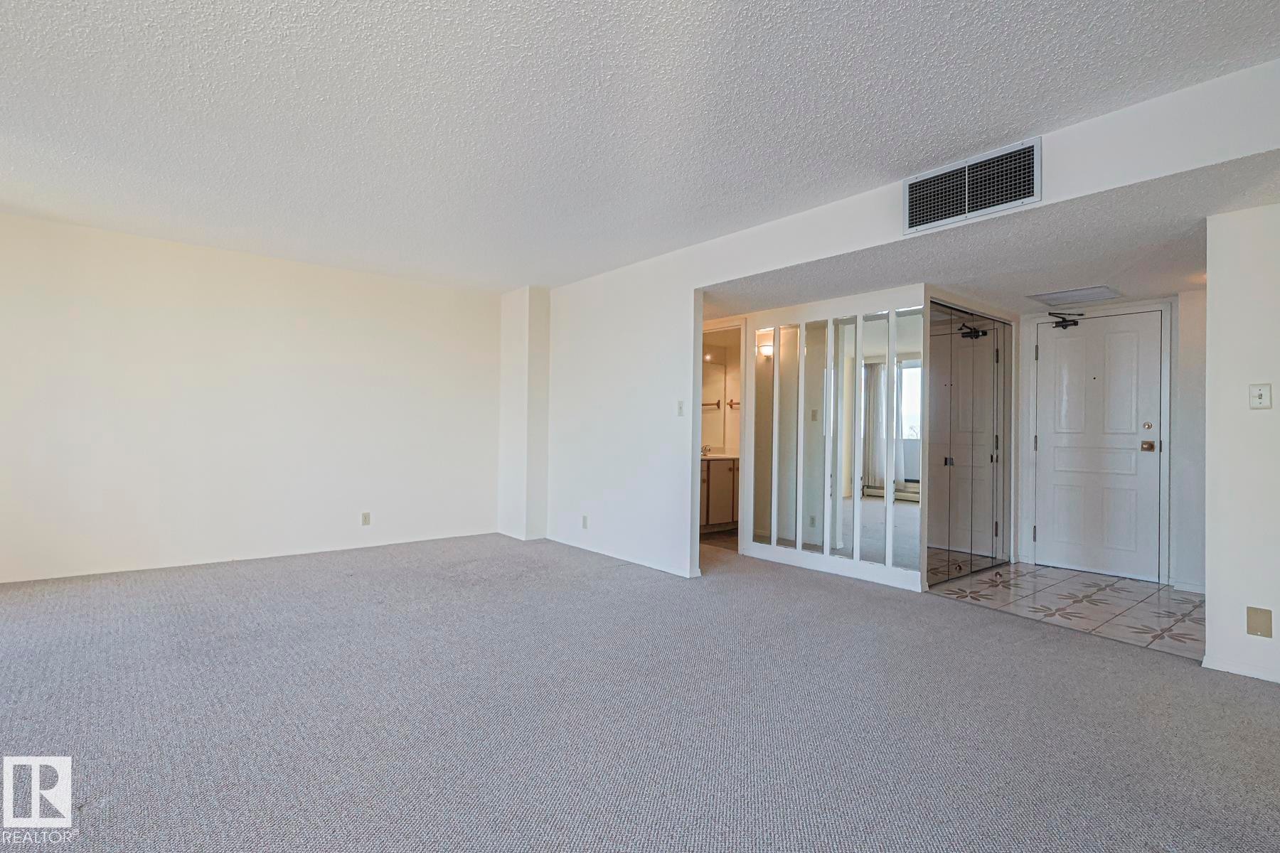 Carpeted spare room with a textured ceiling - 302 8340 Jasper Avenue Nw, Edmonton, AB - Indoor Photo Showing Other Room